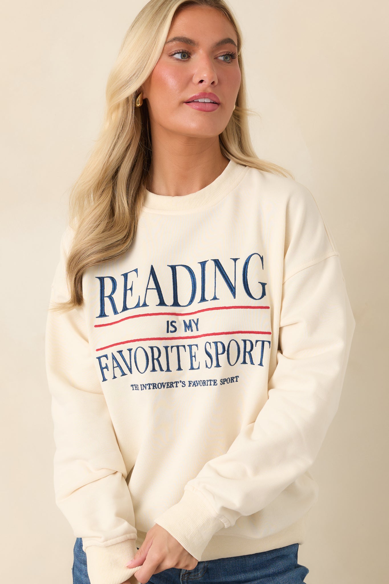 Embroidered navy and red lettering adds a bold contrast to this relaxed ivory crewneck sweatshirt.