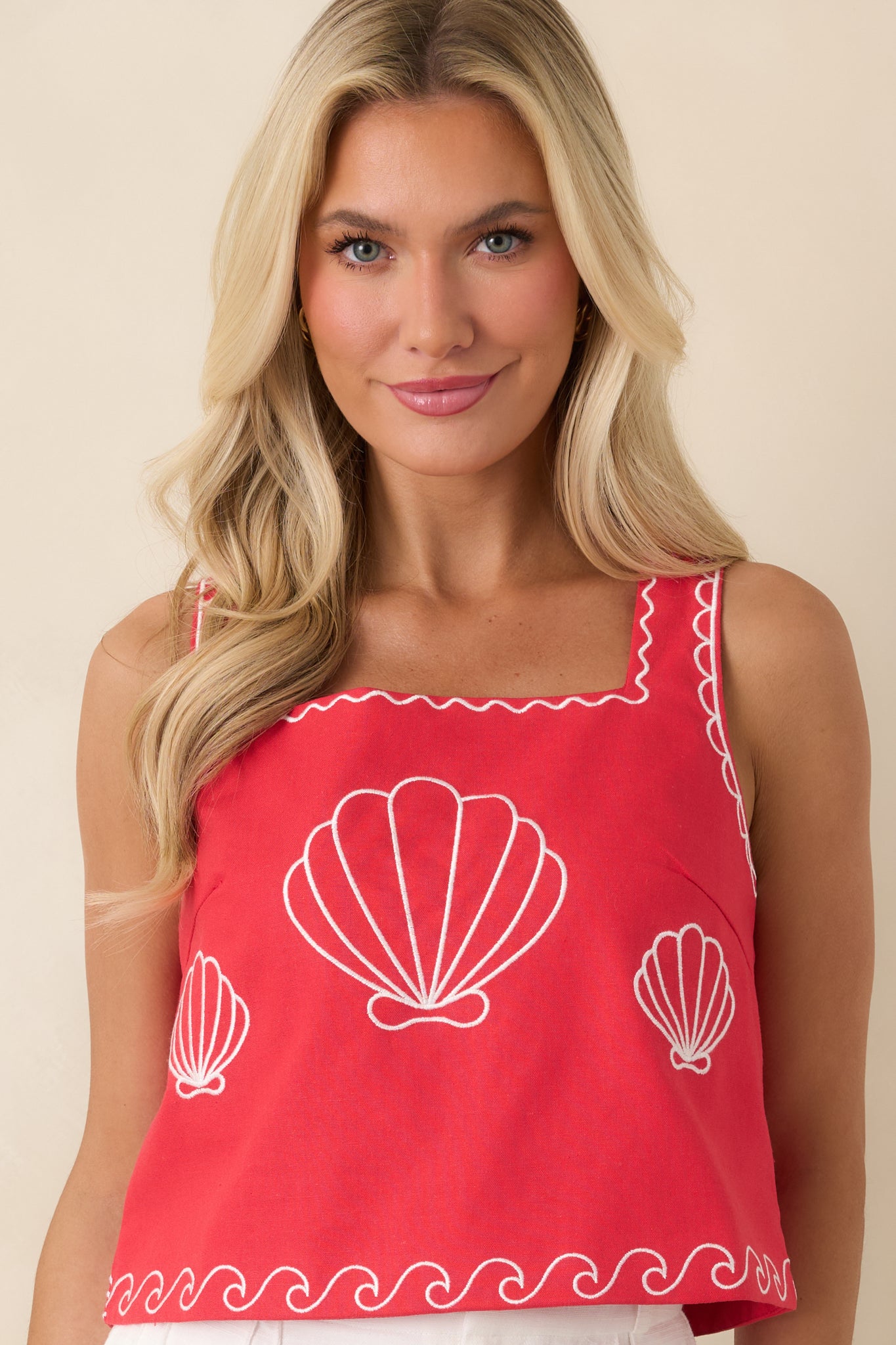 Embroidered shell detail adding texture to structured red top.