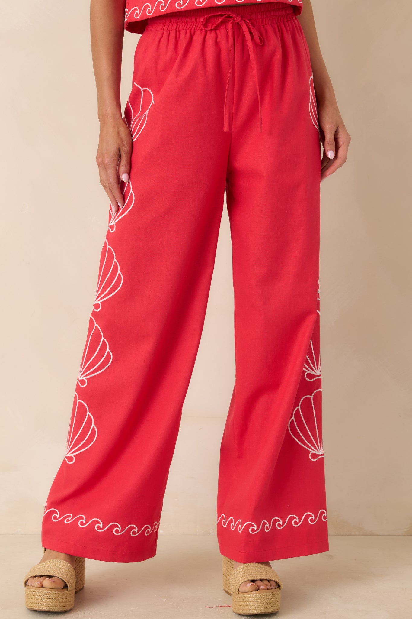 Embroidered shell pattern adding texture to wide leg red pants.