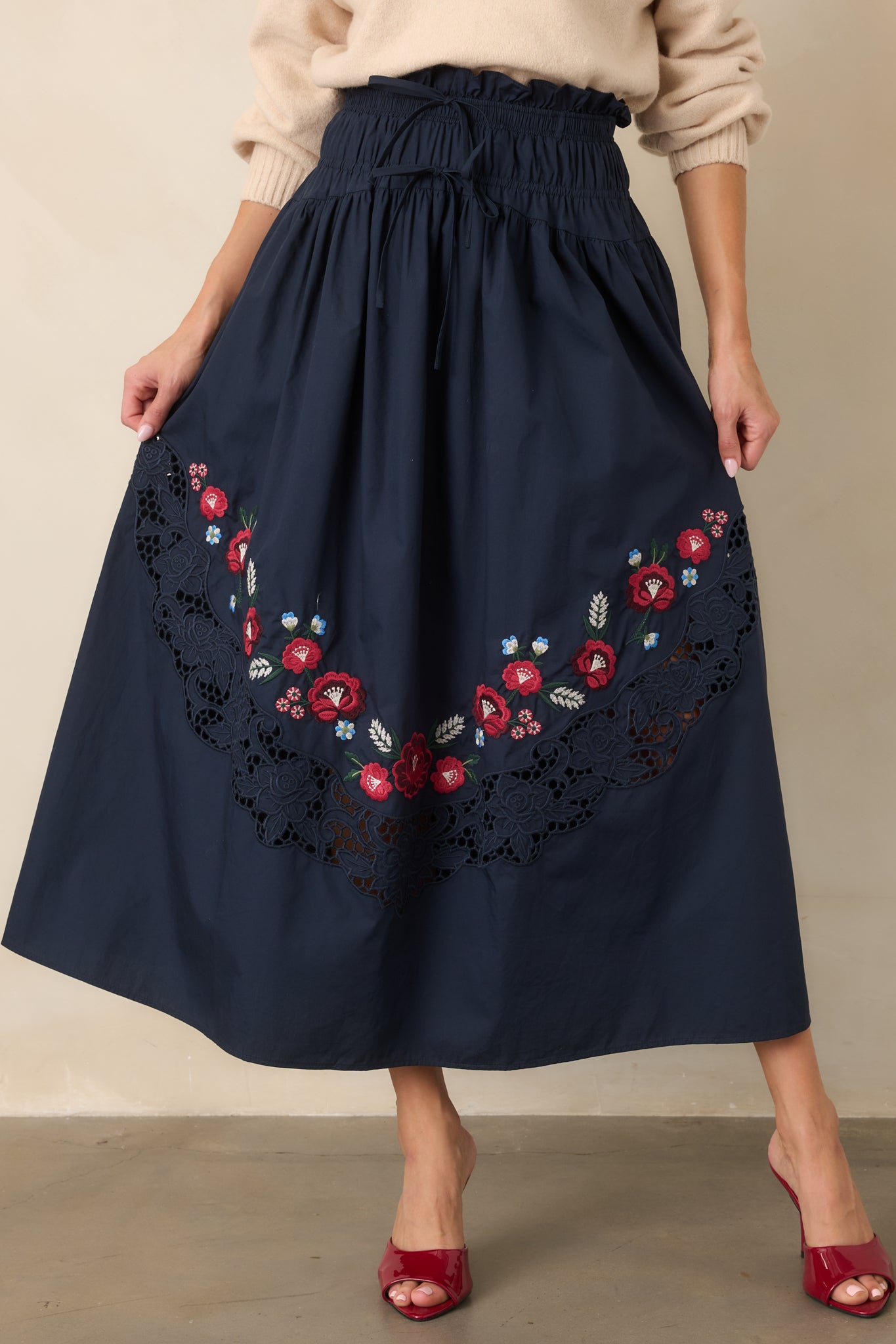 Flowing embroidered skirt with an easy elastic waistband, decorative waist ties, multicolored floral motifs, and a wide lace inset adding intricate texture.