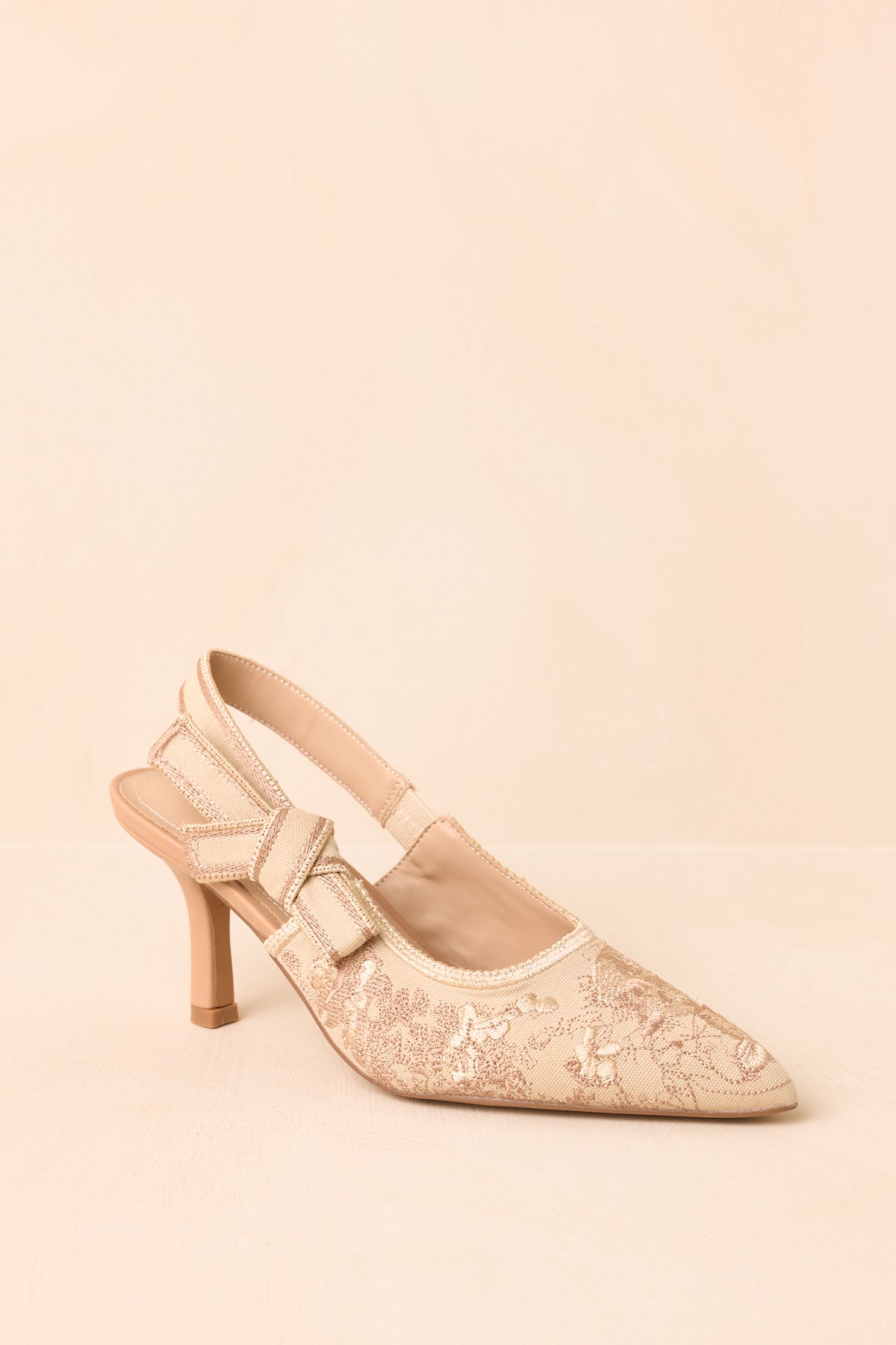 Embroidered soft gold heels displaying their pointed silhouette, contrast detailing, and mid-height heel.