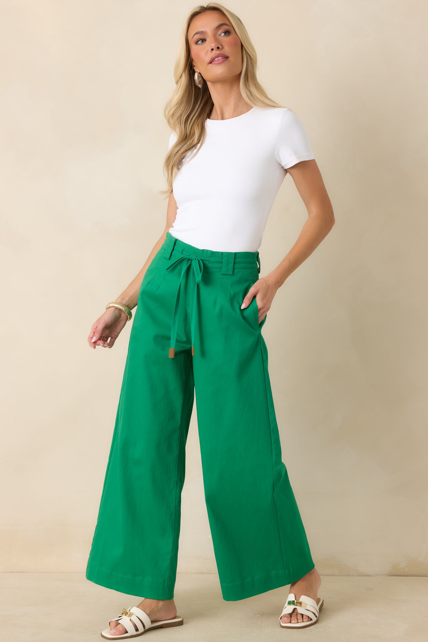 Emerald cotton pants with a flattering high-rise waist, adjustable belt, pleated front, and wide hem.