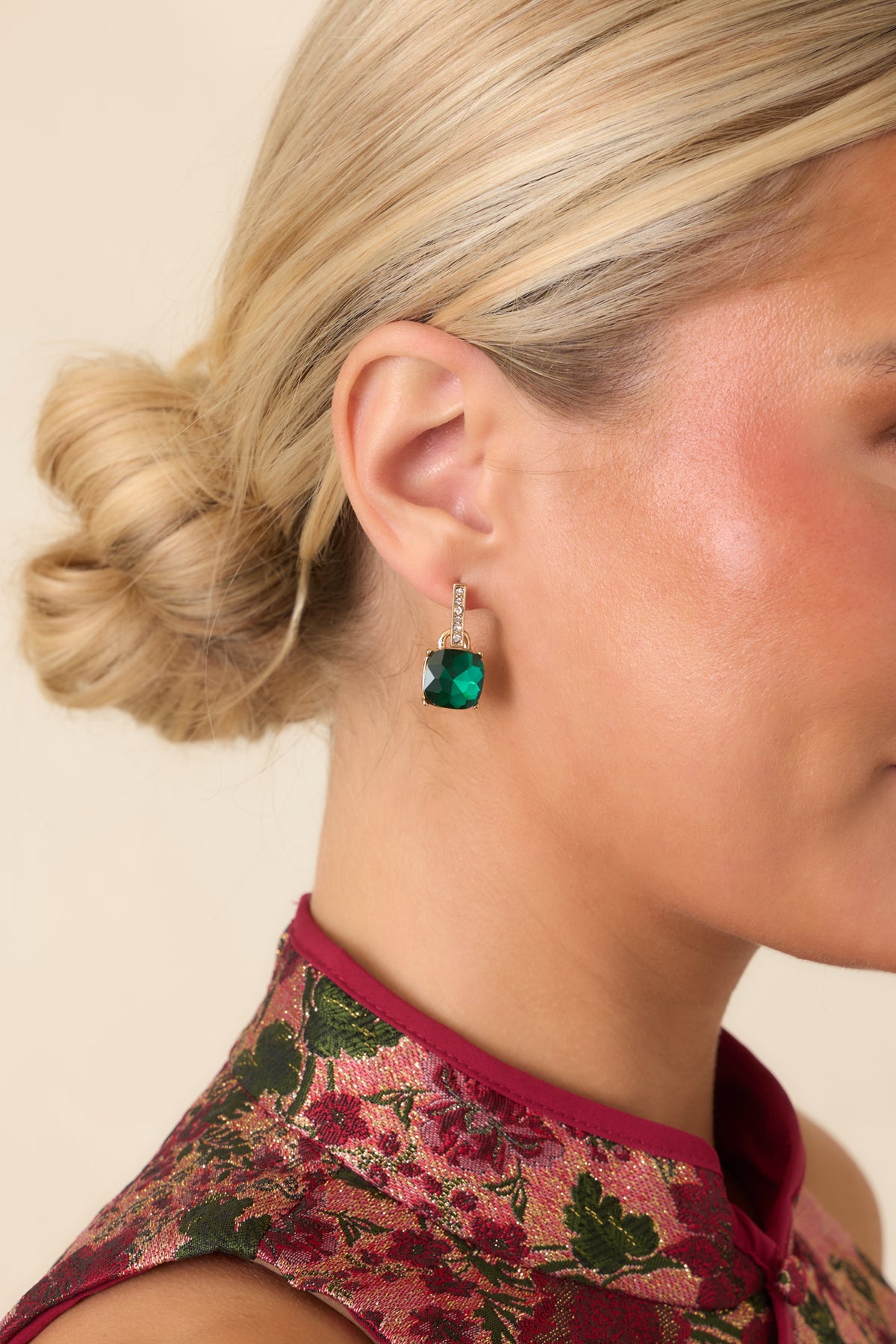 Emerald green cushion-cut earrings suspended beneath slender gold-tone bars accented with tiny crystals.
