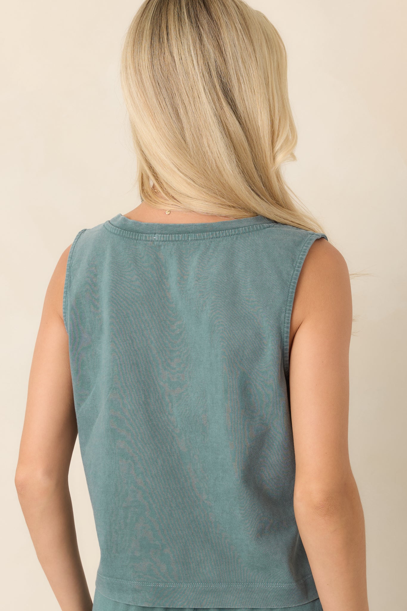 Rear view of the emerald green cotton tank top showing its relaxed fit, sleeveless design, and slightly cropped hem.