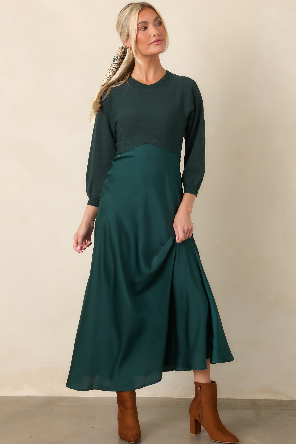Emerald green knit midi dress with a fitted round-neck bodice, three-quarter sleeves, and flowing satin A-line skirt.