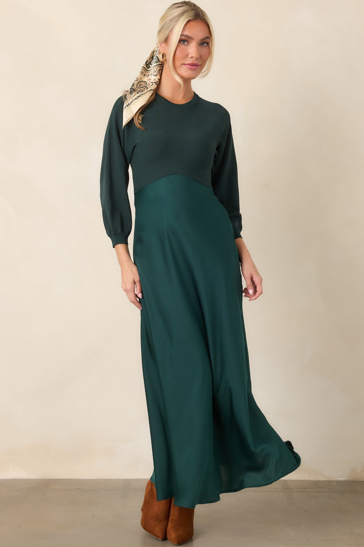 Emerald green dress featuring a classic round neckline, three-quarter knit sleeves, and a high-waisted satin skirt with graceful drape.