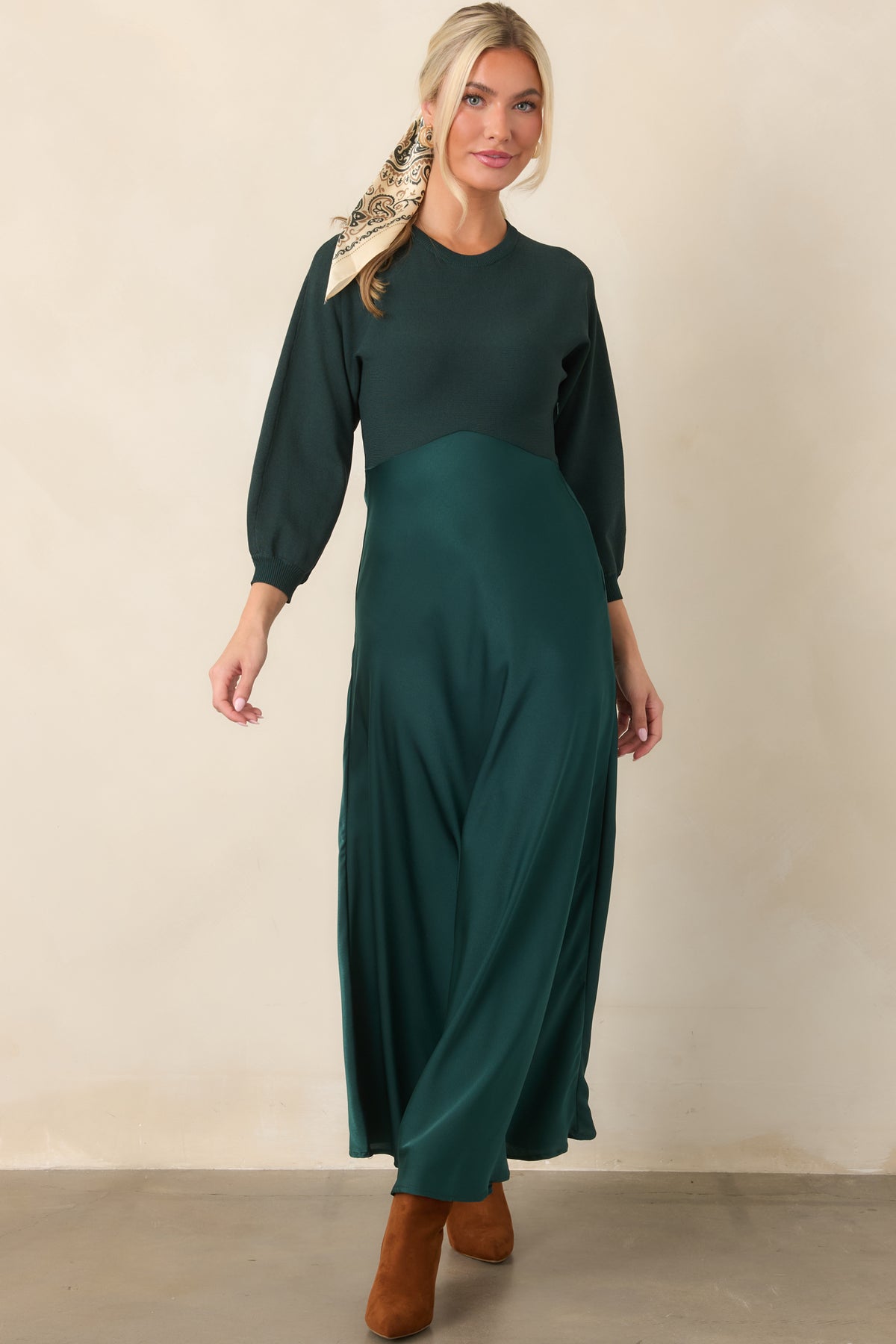 Emerald knit upper bodice with a round neckline and three-quarter sleeves transitions into a softly flowing satin A-line skirt.