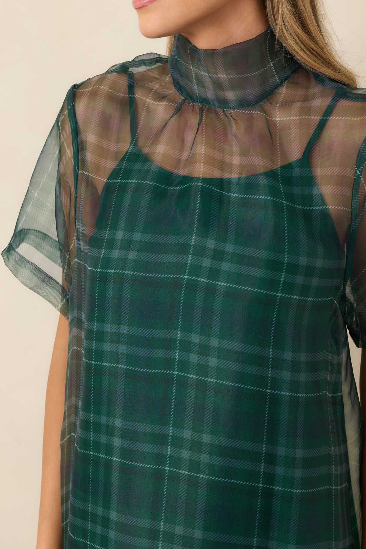Close view of the sheer plaid overlay, high neckline, and delicate fabric layering.