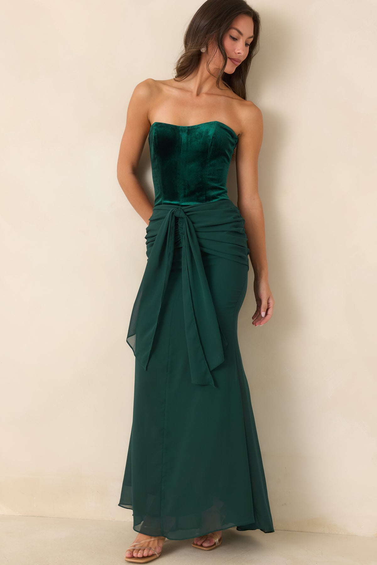 Emerald velvet maxi dress featuring a front draped tie, ruched hips, and softly flowing skirt.