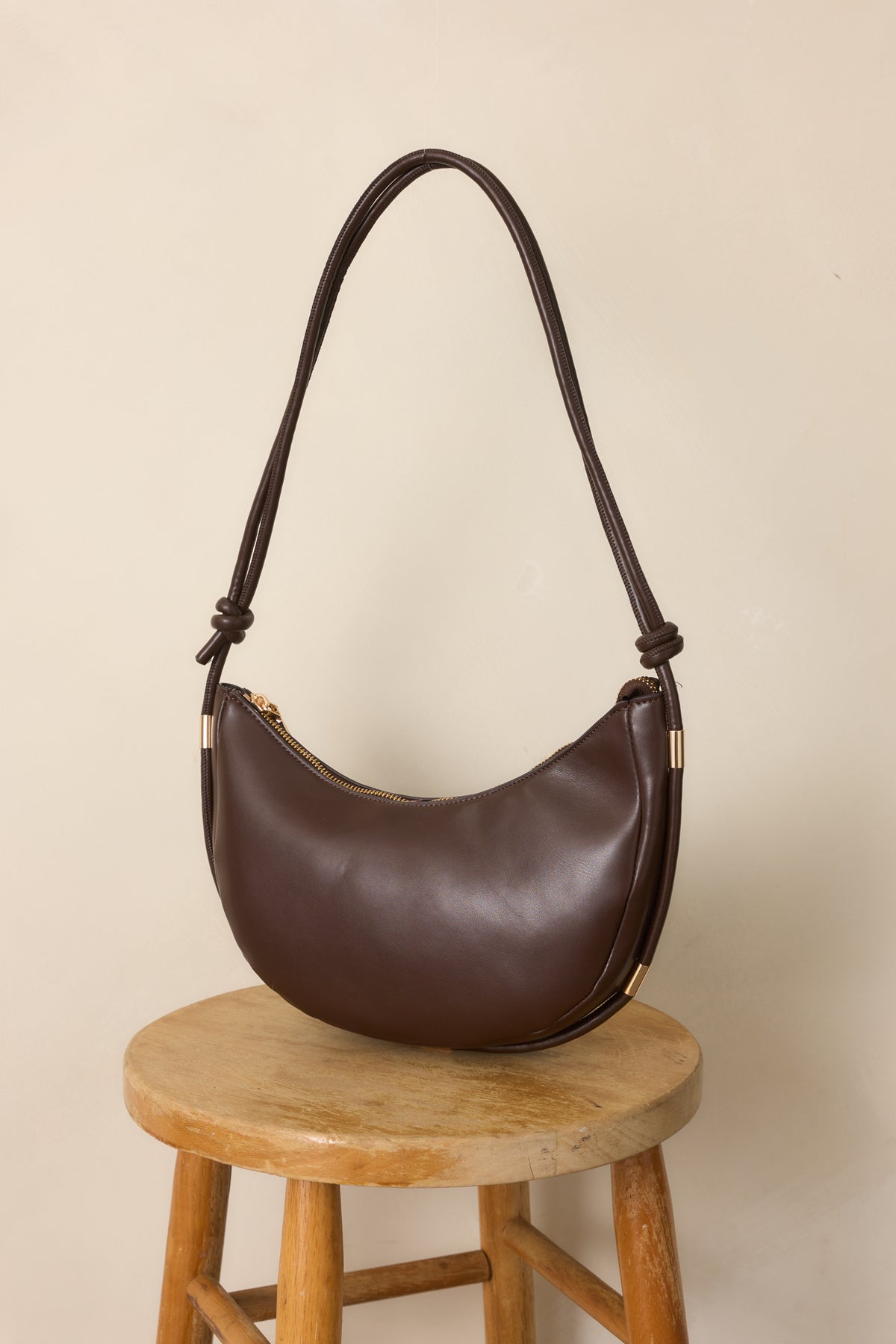 Espresso handbag highlighting the adjustable shoulder strap with intricate knots and polished gold-tone hardware.