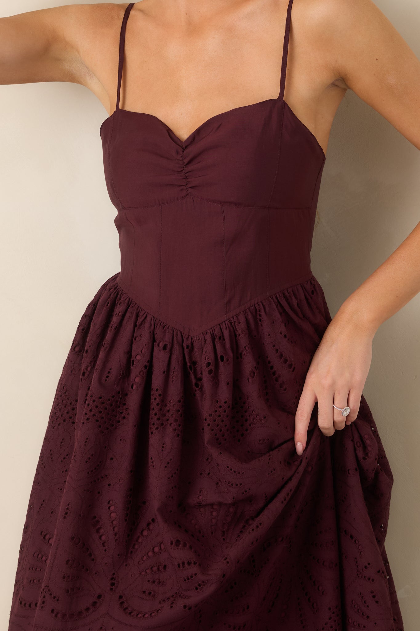 Close-up of the dress highlighting the delicate eyelet fabric, gathered skirt construction, and scalloped hem detailing.