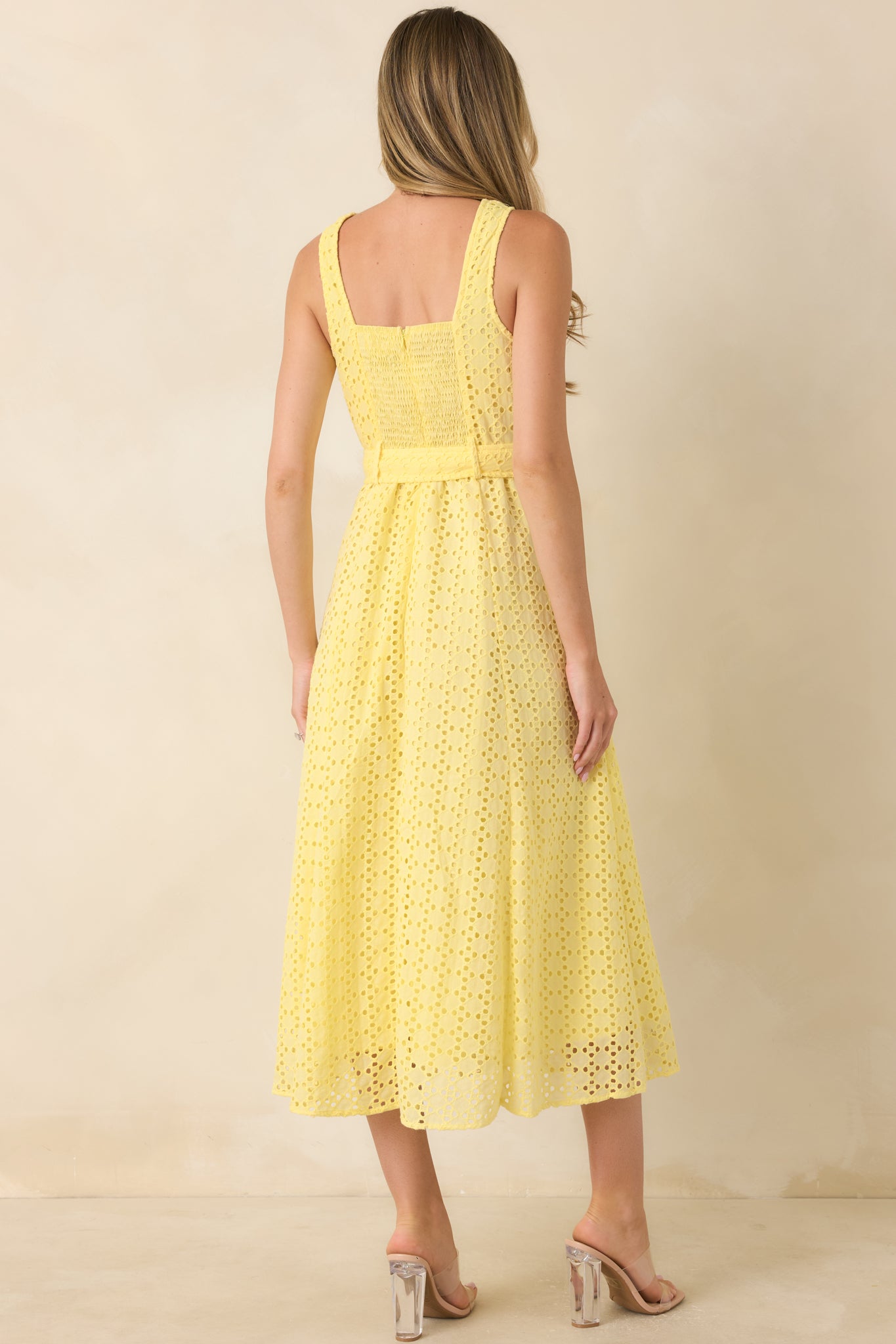 Back view of the sleeveless eyelet midi dress featuring a tailored silhouette and textured fabric design.