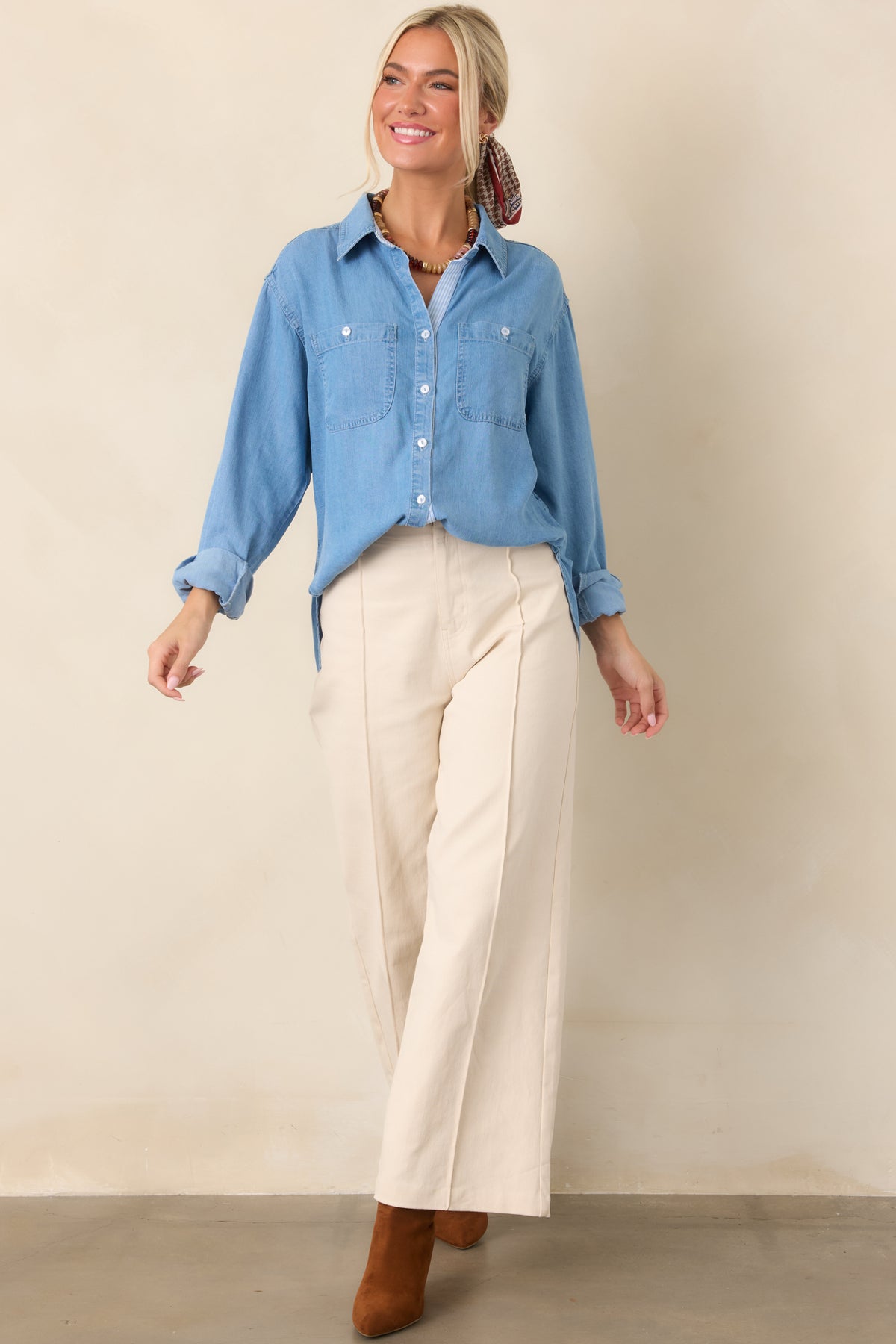 Lived-in denim top showcasing a full button placket, dual utility-style chest pockets, softly faded finish, and high-low hemline.