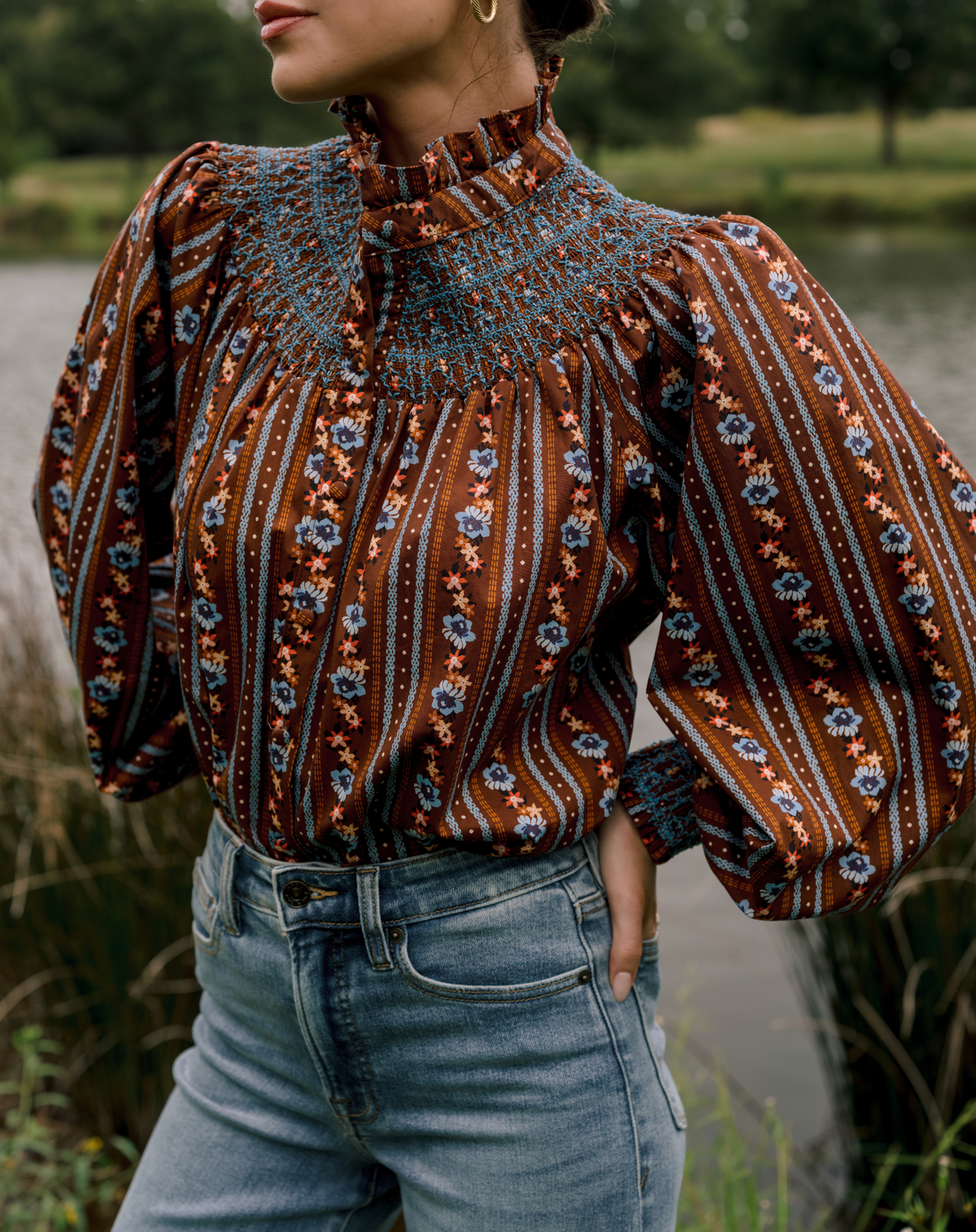 Modeling wearing an orange and blue floral top with jeans.