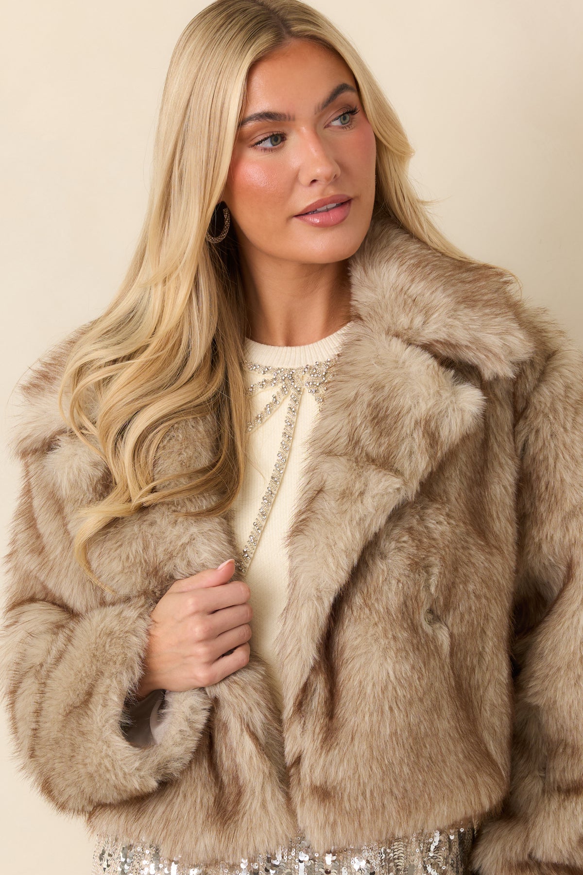 Overlapping front panels of the cropped faux fur jacket secured with a concealed hook closure.