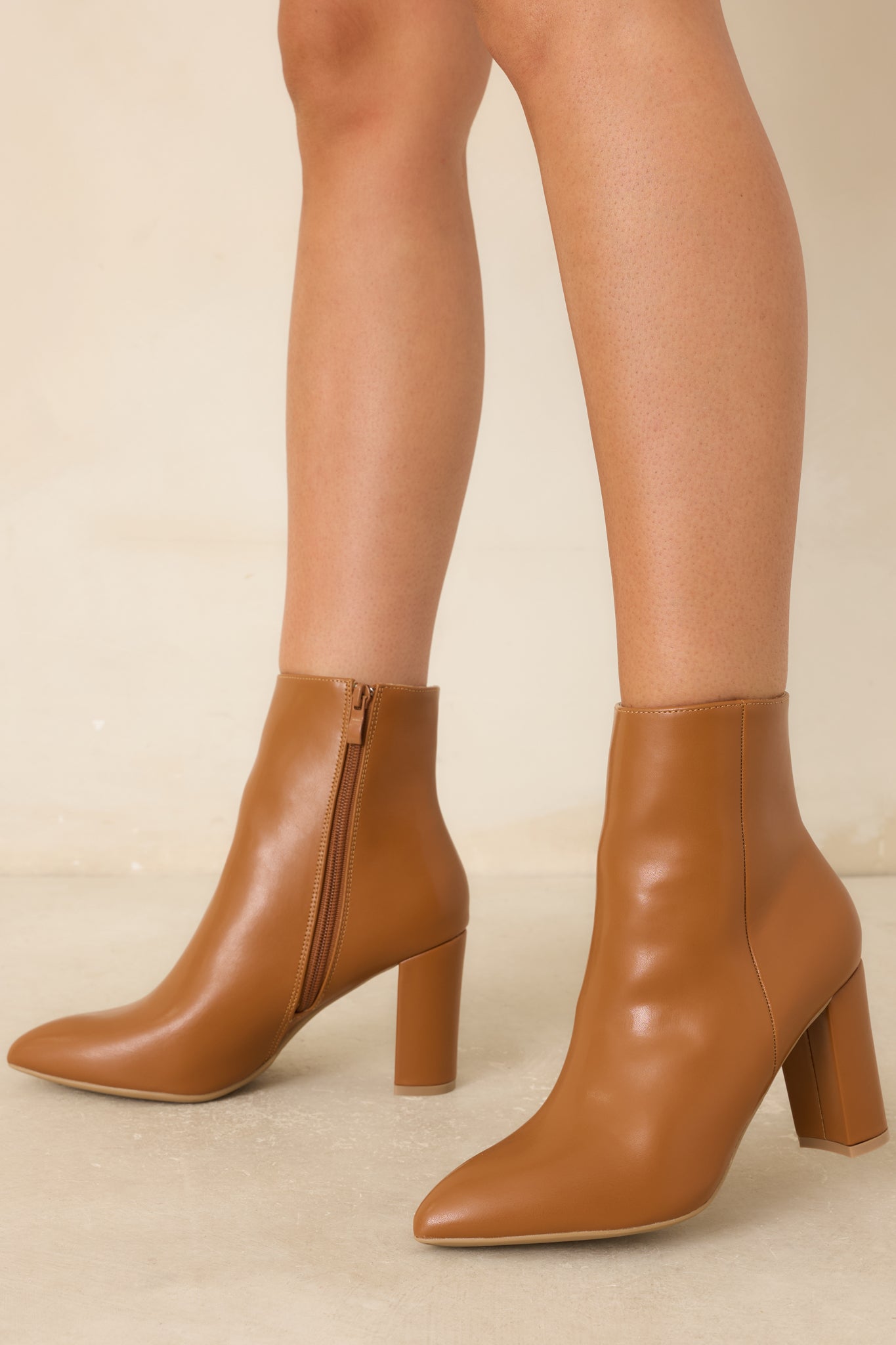 Faux leather ankle boots in a rich caramel brown hue with an inner zipper closure and sleek silhouette.