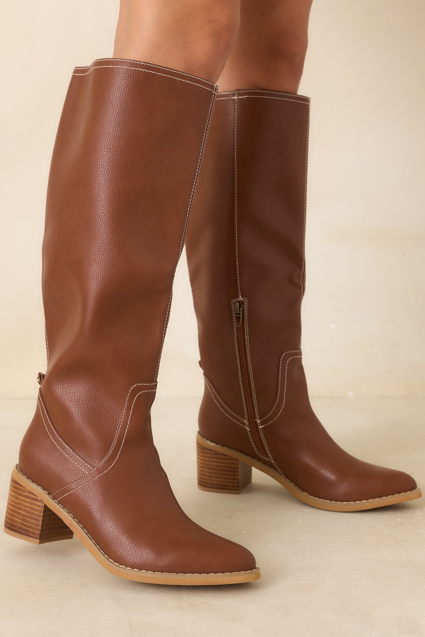 Close view of the boots highlighting the subtle faux leather texture, smooth almond toe shape, and curved stitching details along the design.
