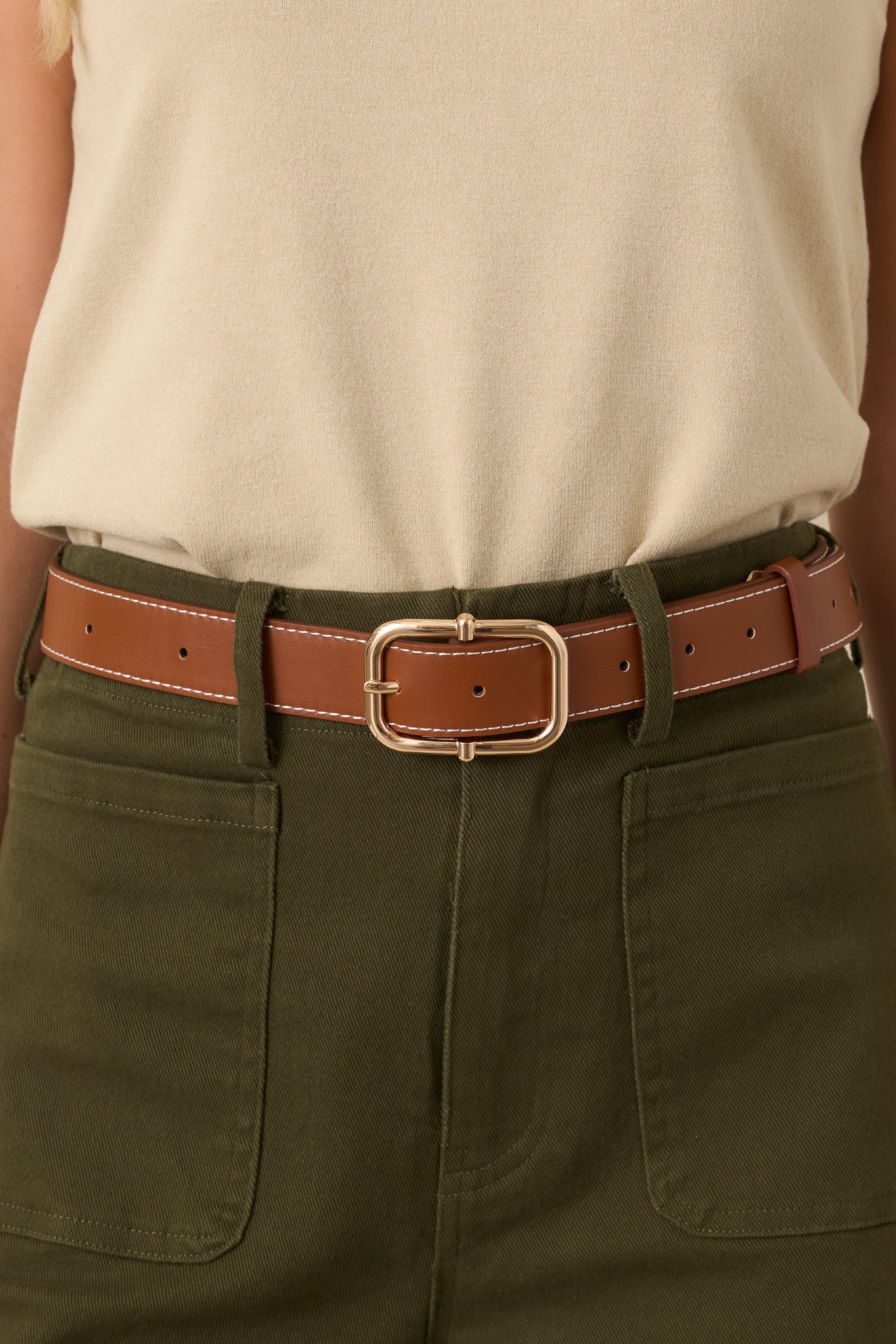 Faux leather brown belt with contrast ivory stitching, a polished square buckle, and a coordinating belt keeper.