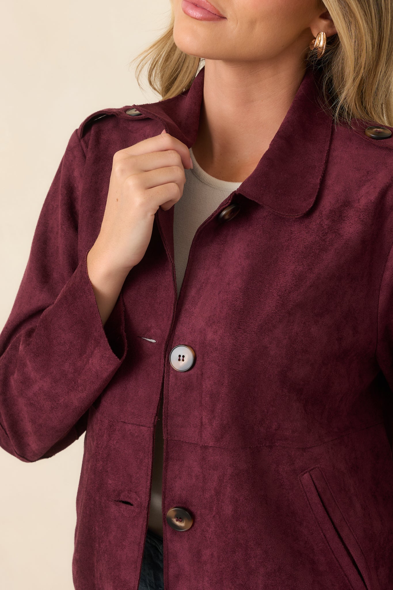 Close-up of the faux suede fabric showcasing the rounded collar, functional buttons, shoulder tab detailing, and smooth textured finish.