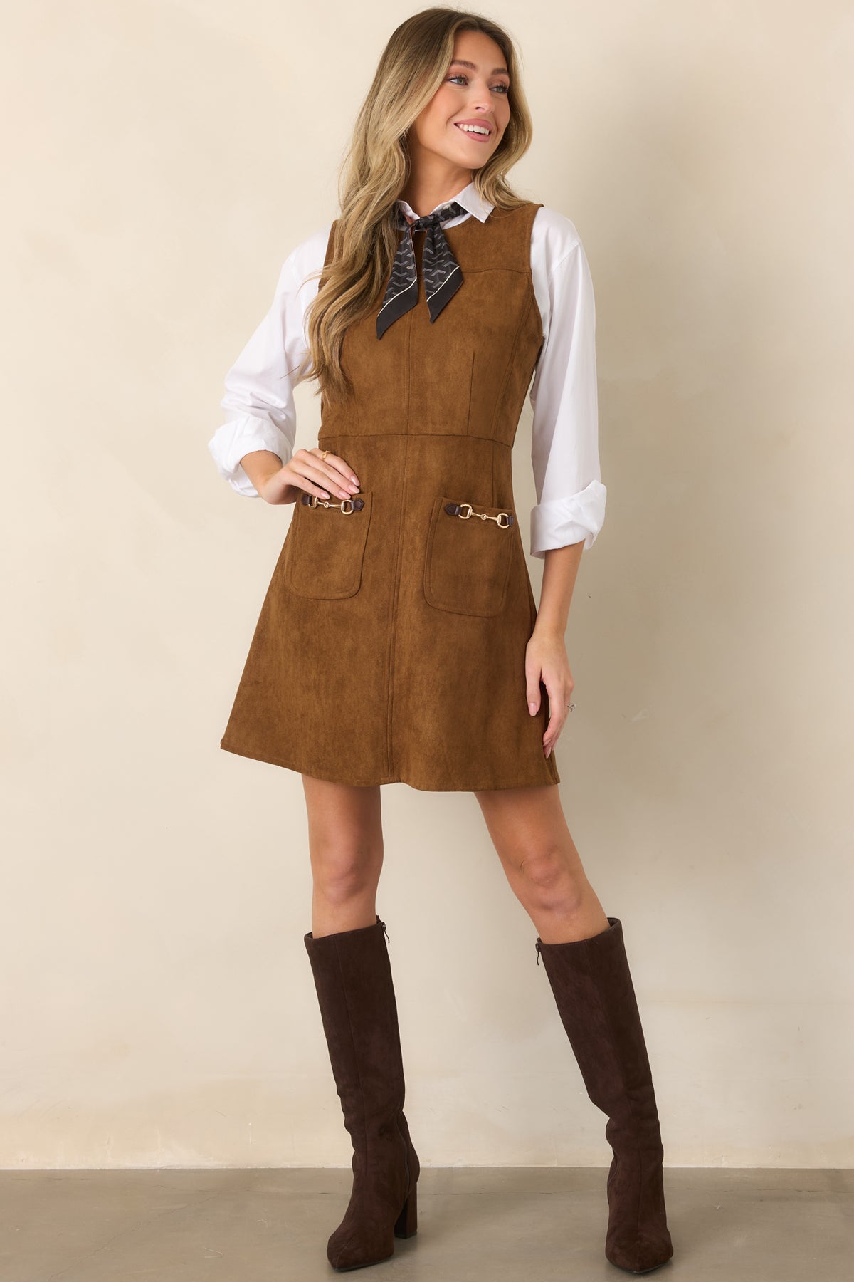 Refined faux suede mini dress with a clean round neck, sleeveless silhouette, tailored seams, fitted waist, and softly flared hem.