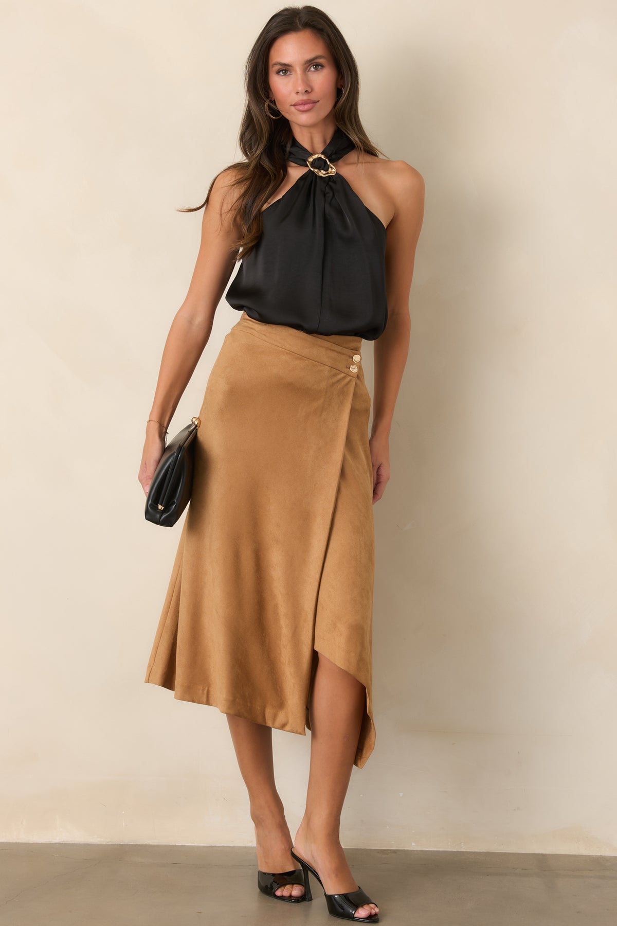 Stretch faux suede skirt features a high-rise waist, asymmetrical wrap front, hammered gold-tone buttons, and angled hem.