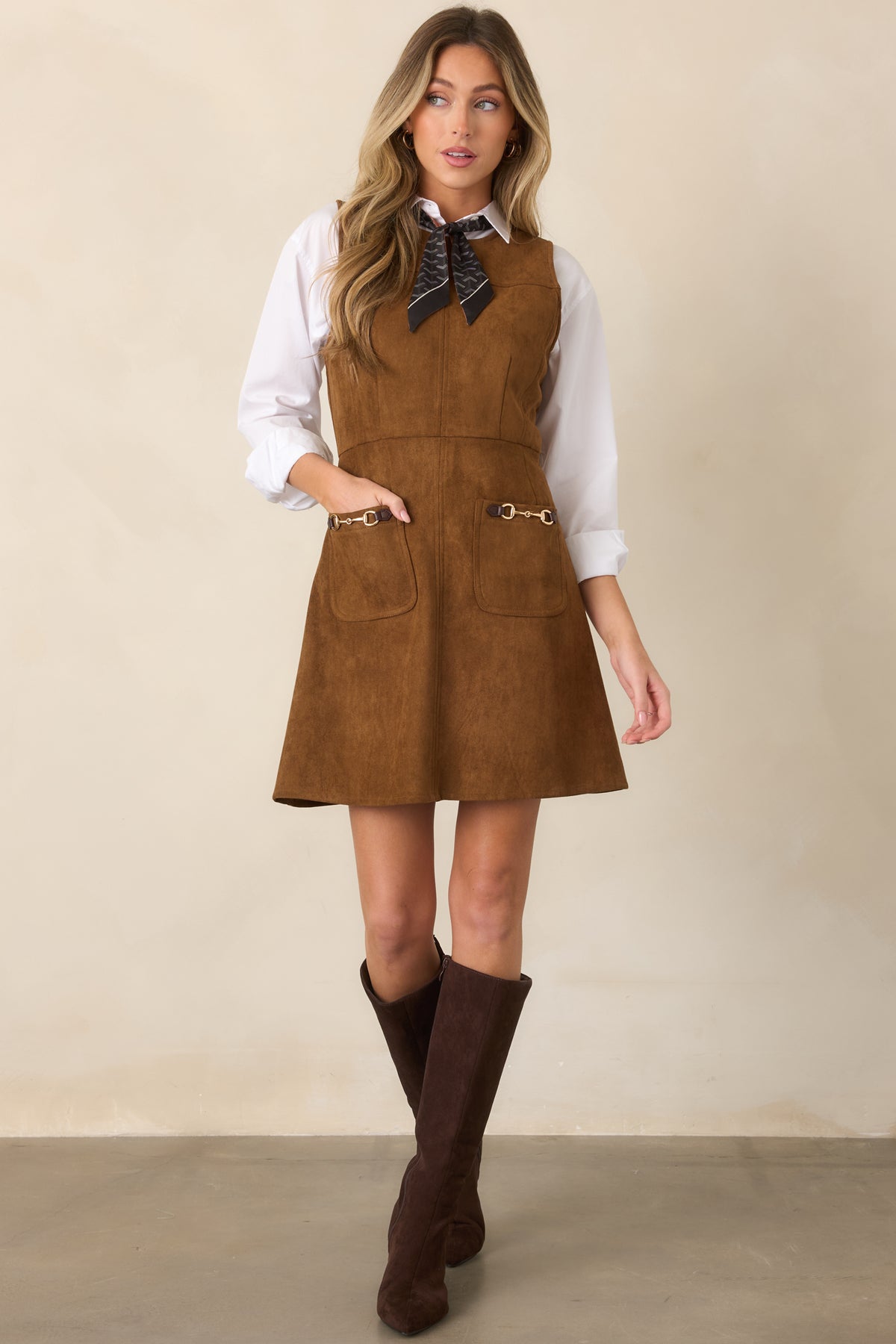 Sleeveless faux suede dress showcasing a structured bodice, defined waistline, gently flared mini skirt, and front patch pockets with gold-tone hardware.