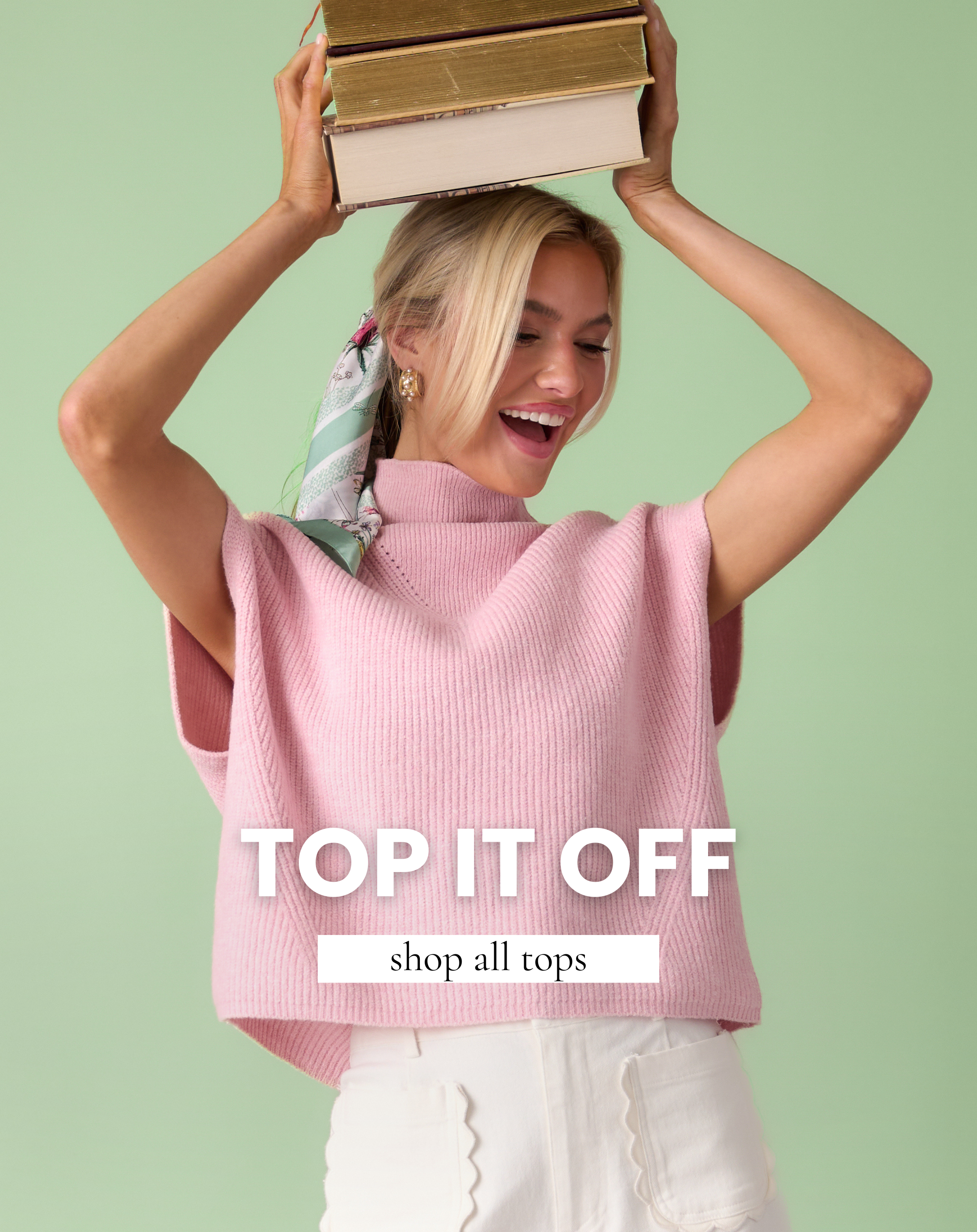 Woman wearing a pink sleeveless knit top with a high neckline, styled with white pants against a light green background.