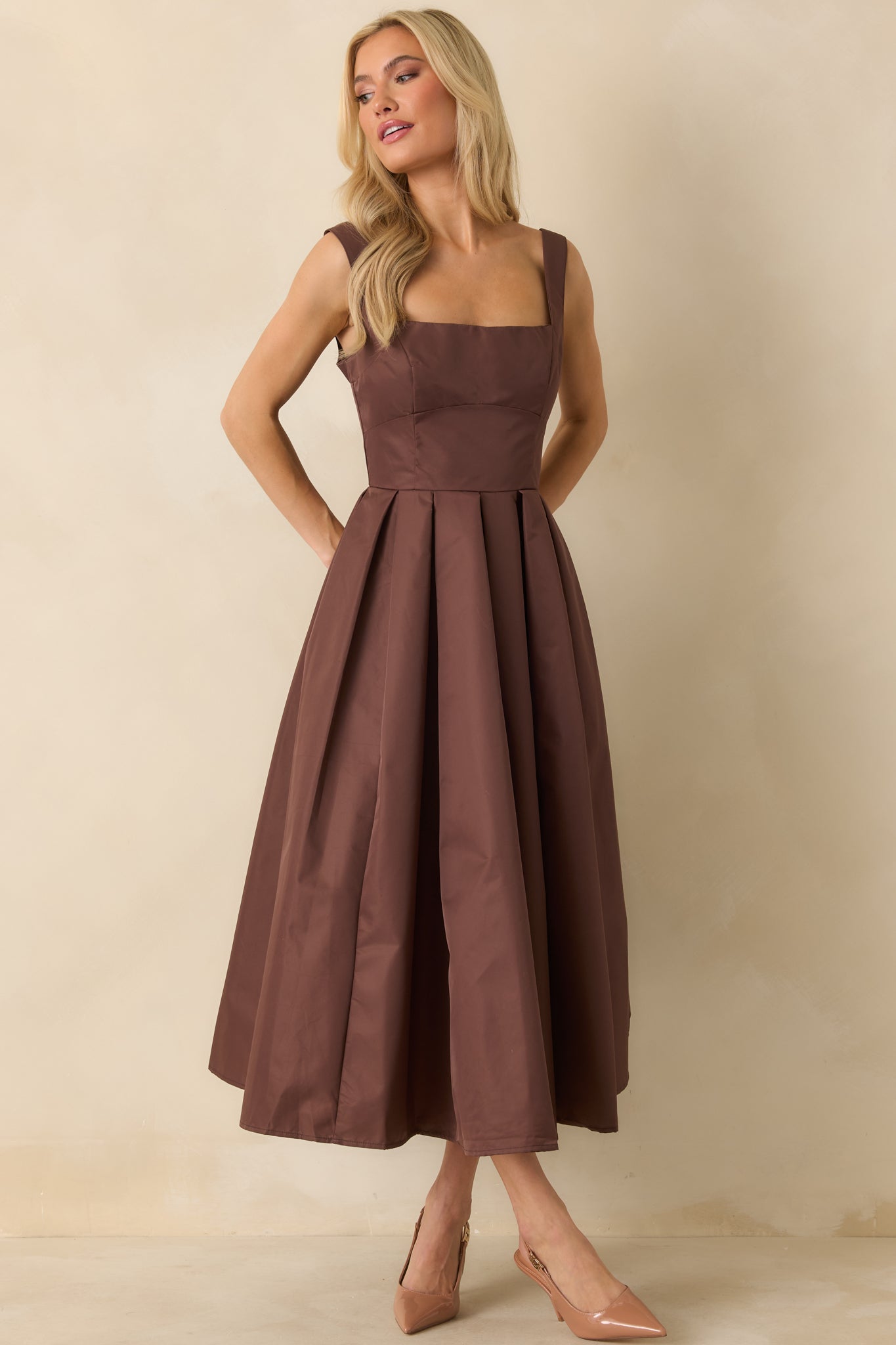 Dress featuring fitted bodice with thick woven material and defined pleats.