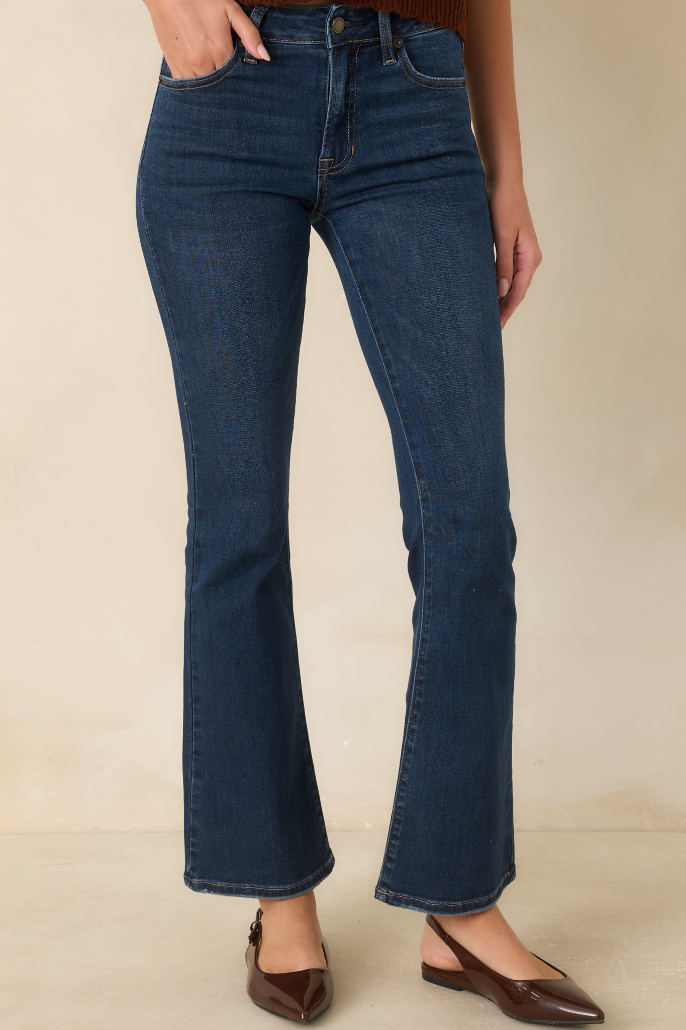 Detailed view highlighting the fitted upper silhouette, dark wash finish, and crisp contrast stitching across the front of the jeans.
