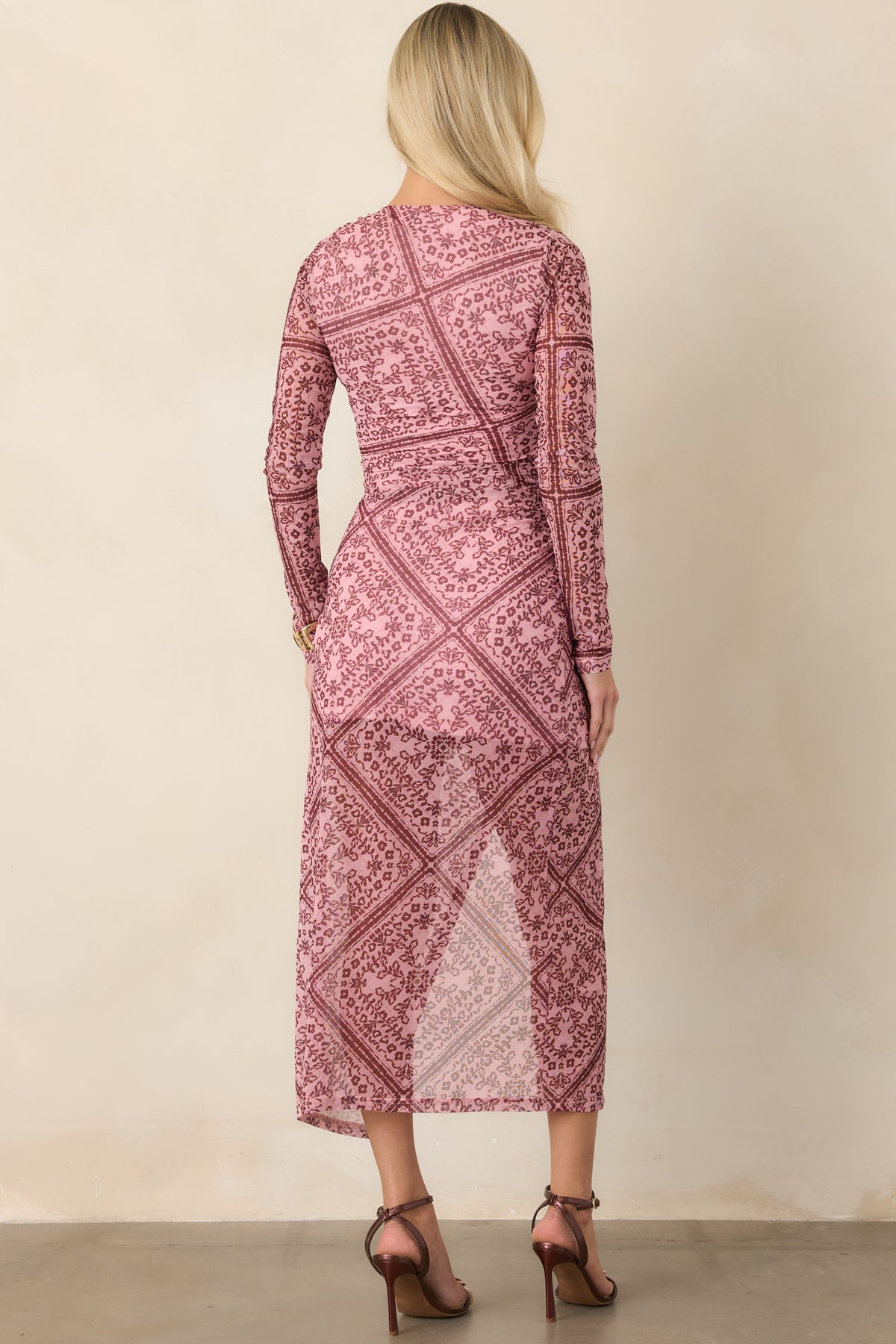 Rear of the fitted mesh dress showcasing the ruched waist, sheer long sleeves, and shorter lining beneath the skirt.