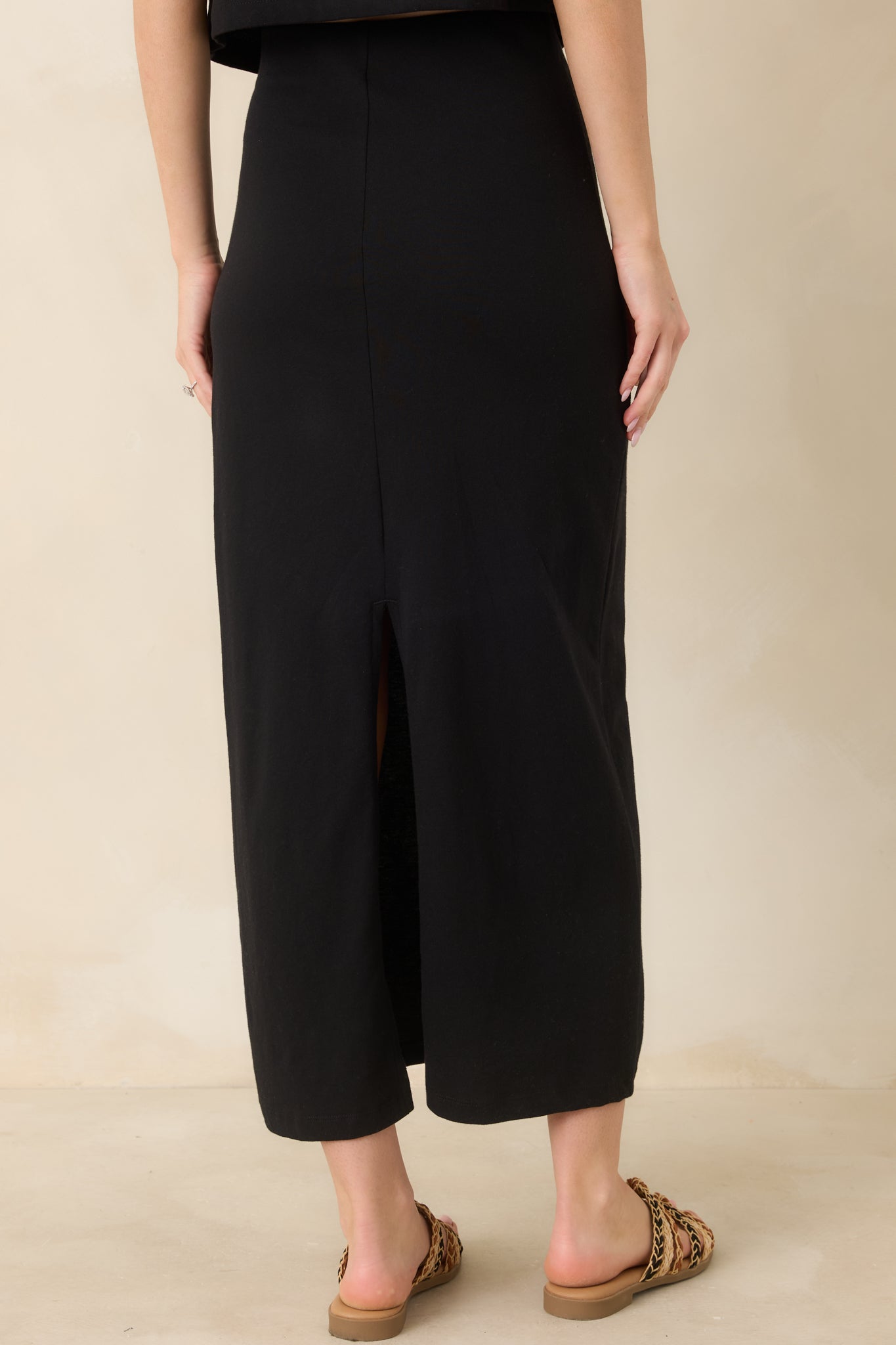 Fitted midi skirt with back slit and streamlined rear silhouette.

