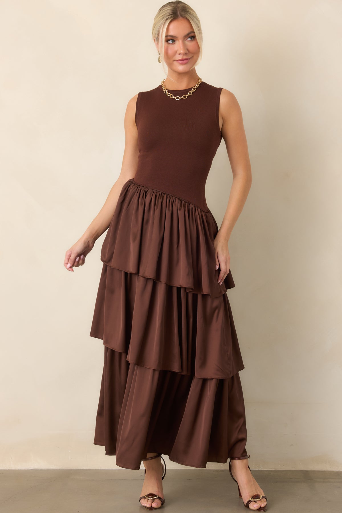Fitted sleeveless bodice transitions into layered woven panels beneath the diagonal waist seam for a fluid silhouette.