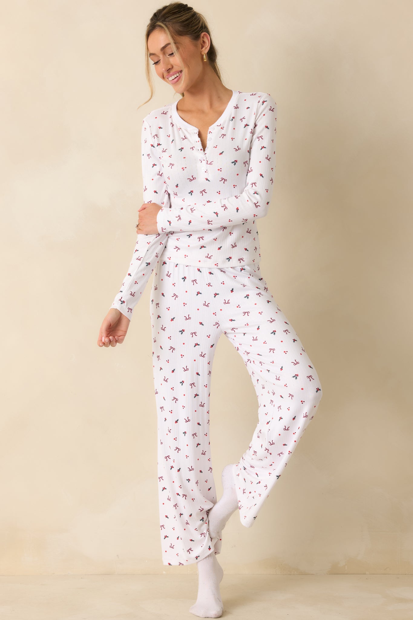 Fitted white henley top featuring a soft-wash finish and festive holly-and-bow pattern throughout the fabric.