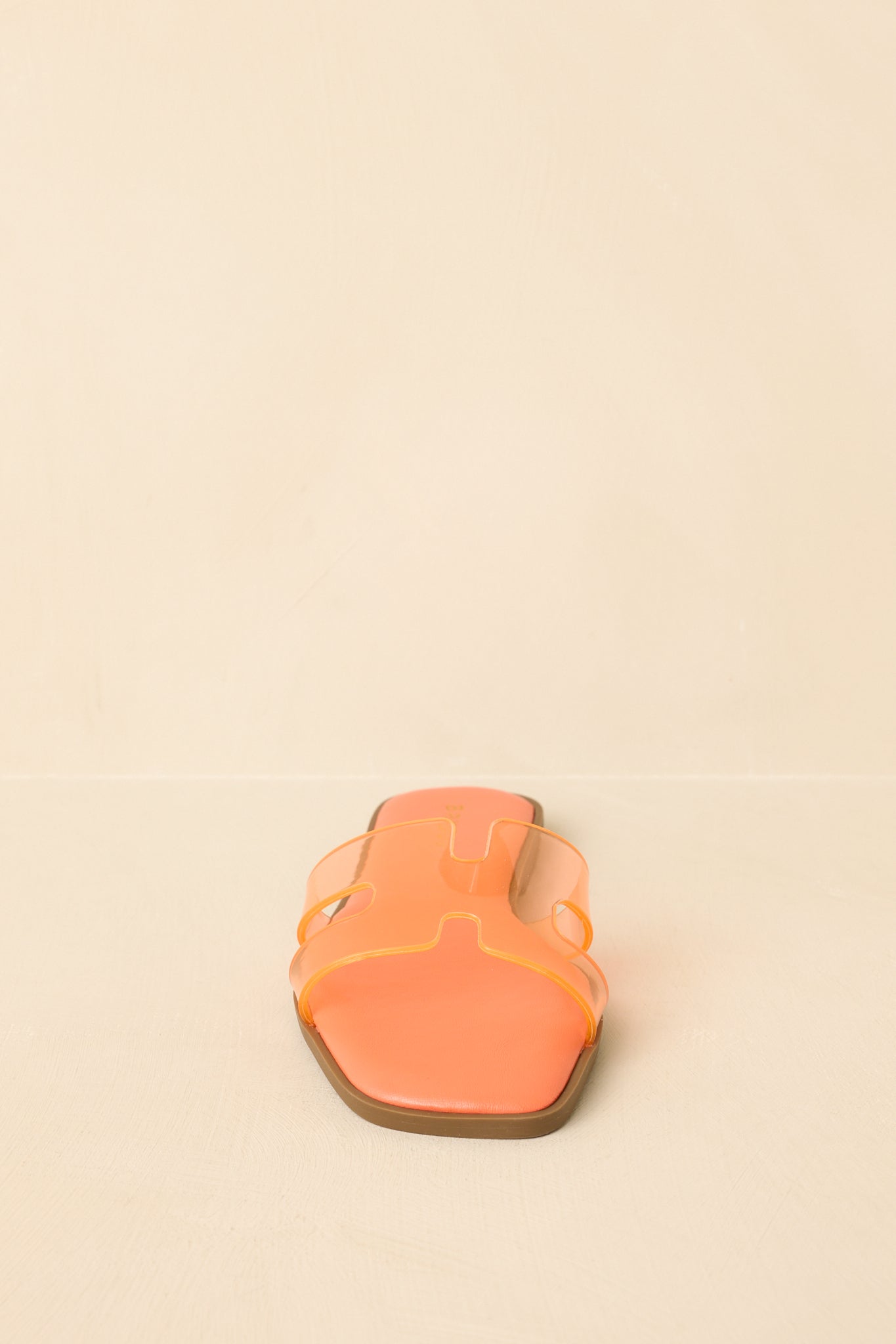 Flat slide sandals displayed from a straight-on angle emphasizing the square toe and vibrant orange base.