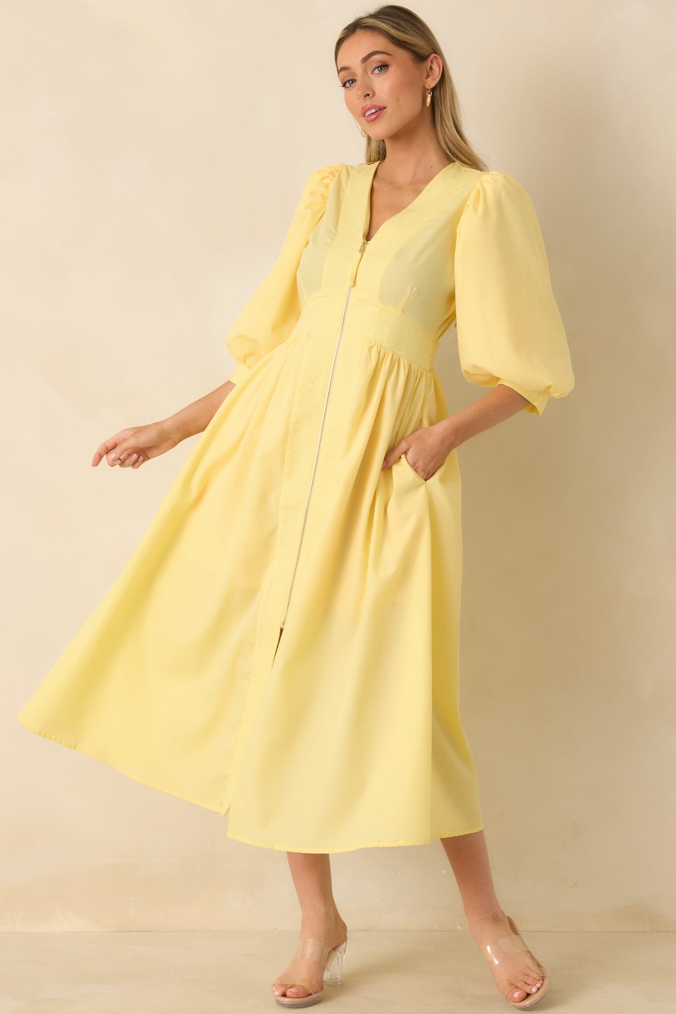 Flattering yellow midi dress with a V-neck, soft pleating in the skirt, and functional side pockets for ease and style.