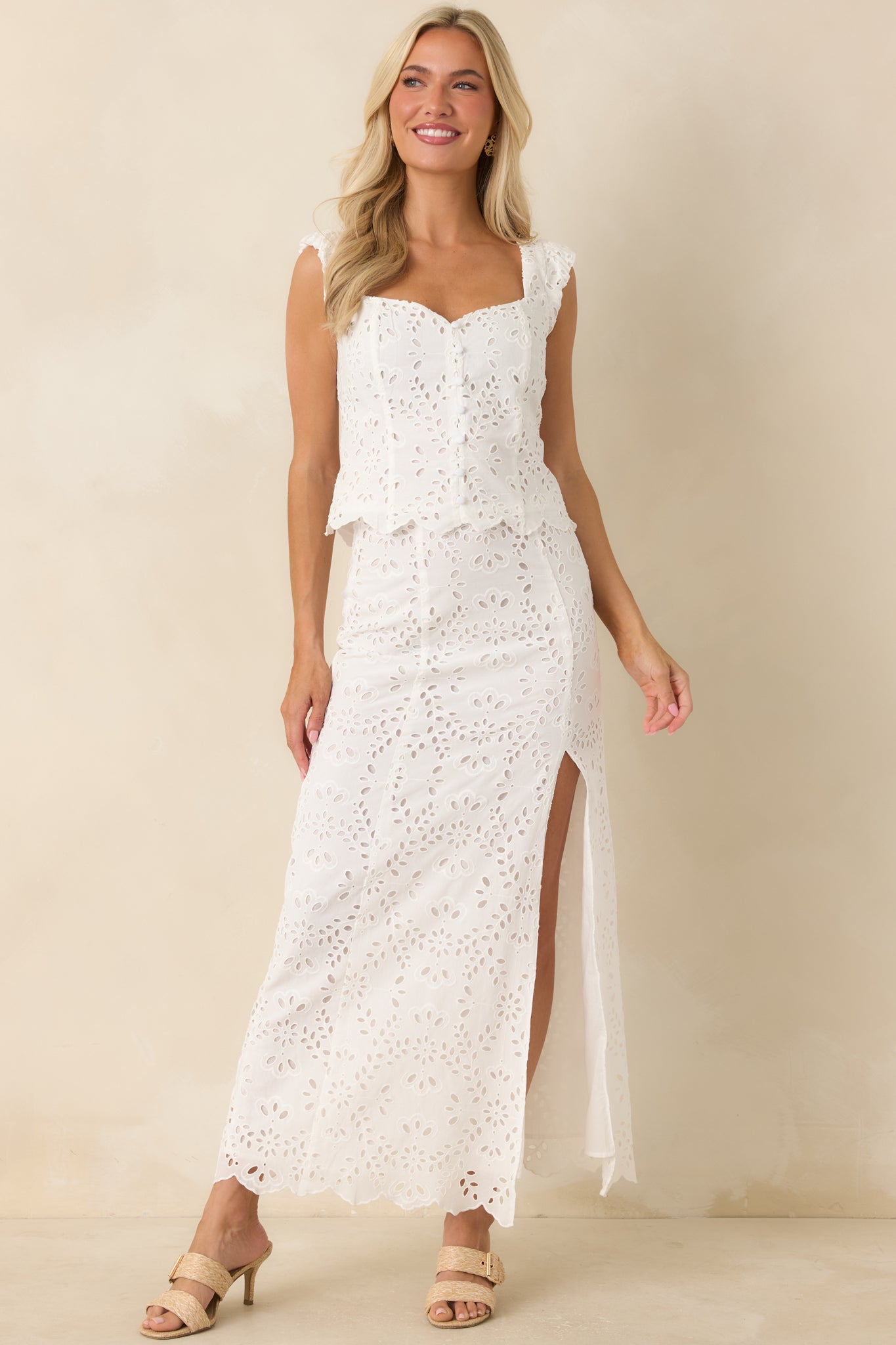Fully lined white maxi skirt showcasing intricate floral eyelet detailing and a graceful floor-grazing silhouette.