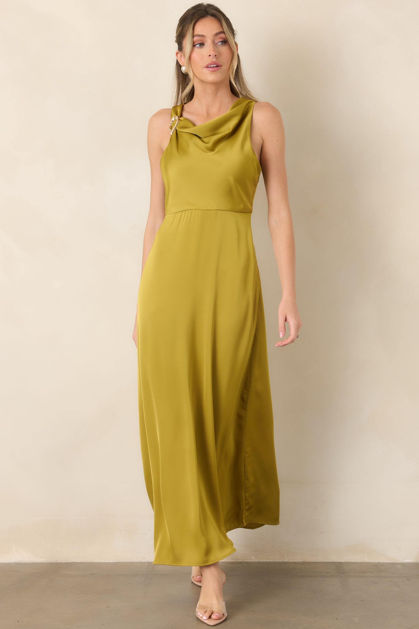 Floor-length satin dress highlighting its softly gathered bodice, sculptural gold-tone shoulder feature, and elegant flowing skirt.