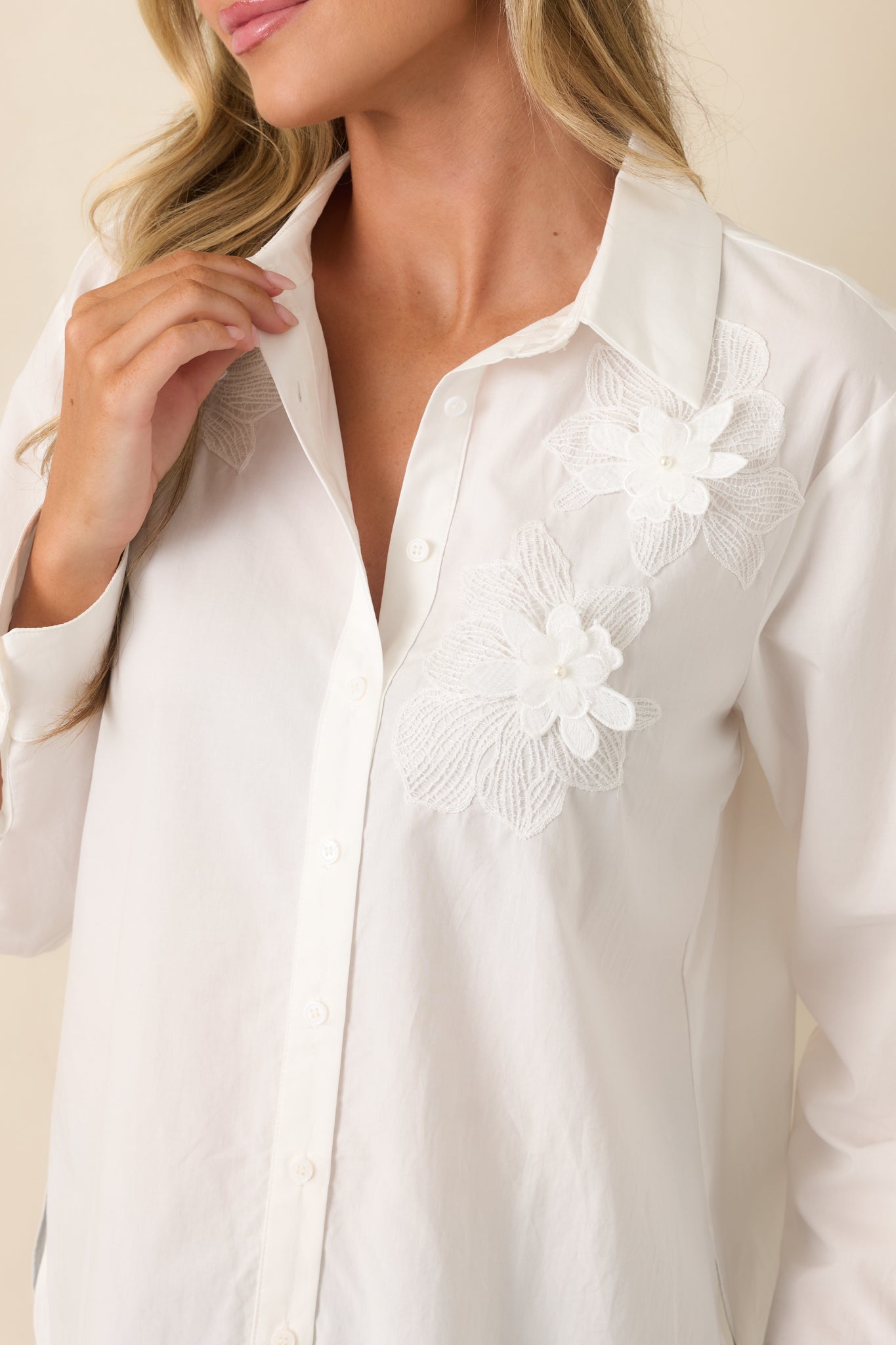 Close-up of the blouse highlighting the delicate floral appliqué stitching, lightweight woven texture, and refined front detailing.