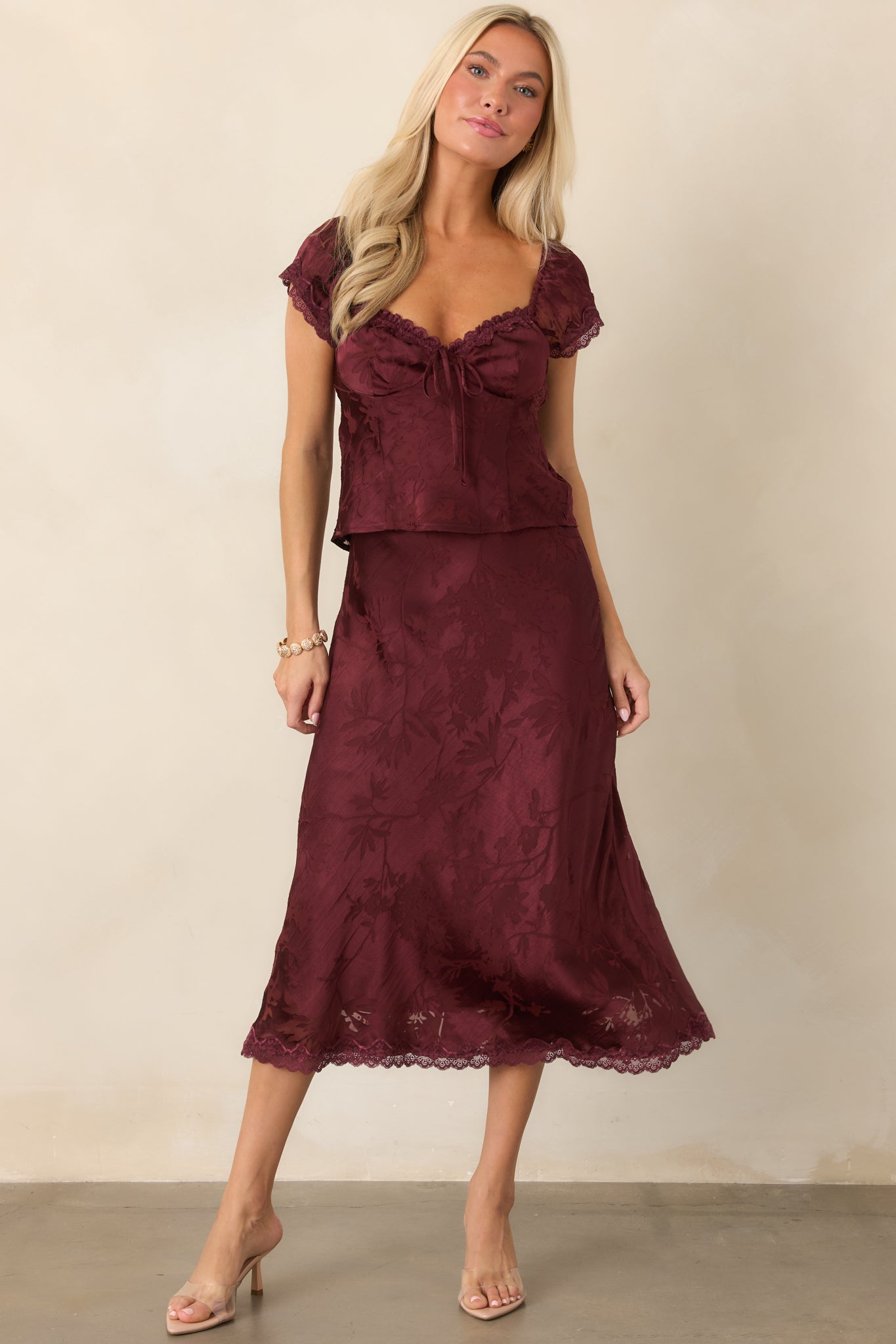Textured floral burnout top displaying a sweetheart neckline, dainty tie detail, gently voluminous cap sleeves, and sleek fitted shape.
