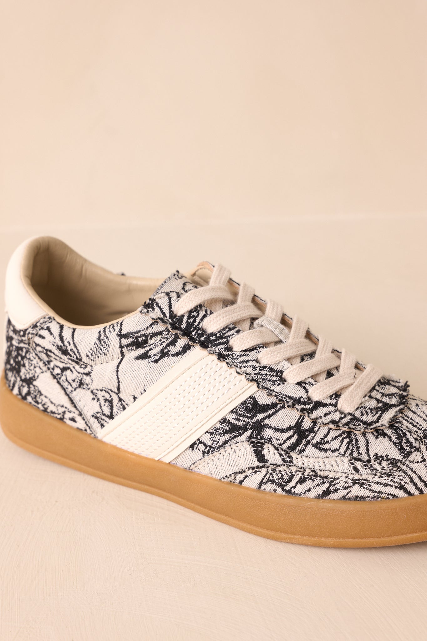 Close-up of the floral canvas and cream faux leather overlays with gum rubber sole edge.
