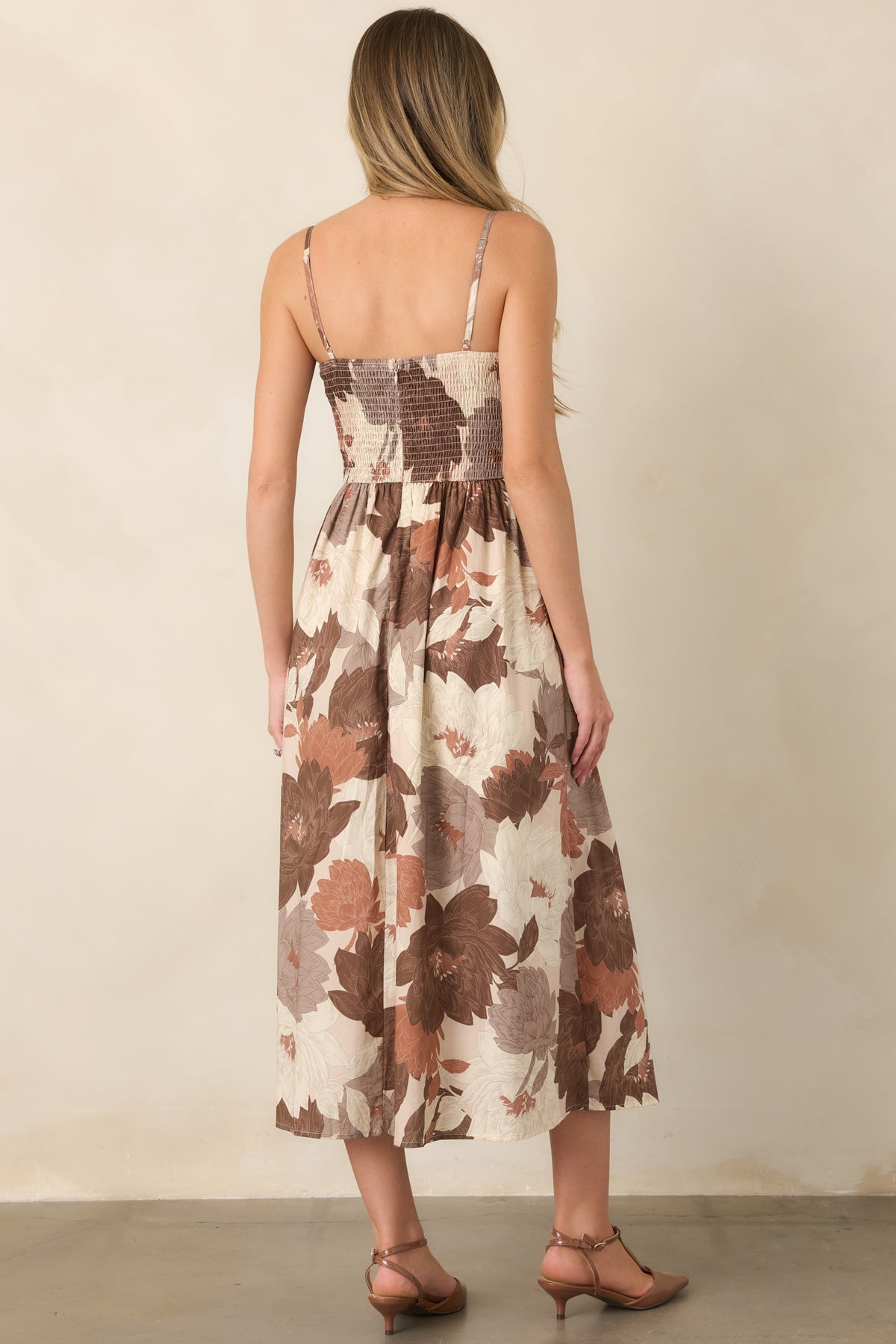 Rear of the floral cotton midi dress showing the smocked back, adjustable straps, defined waist, and full A-line skirt.