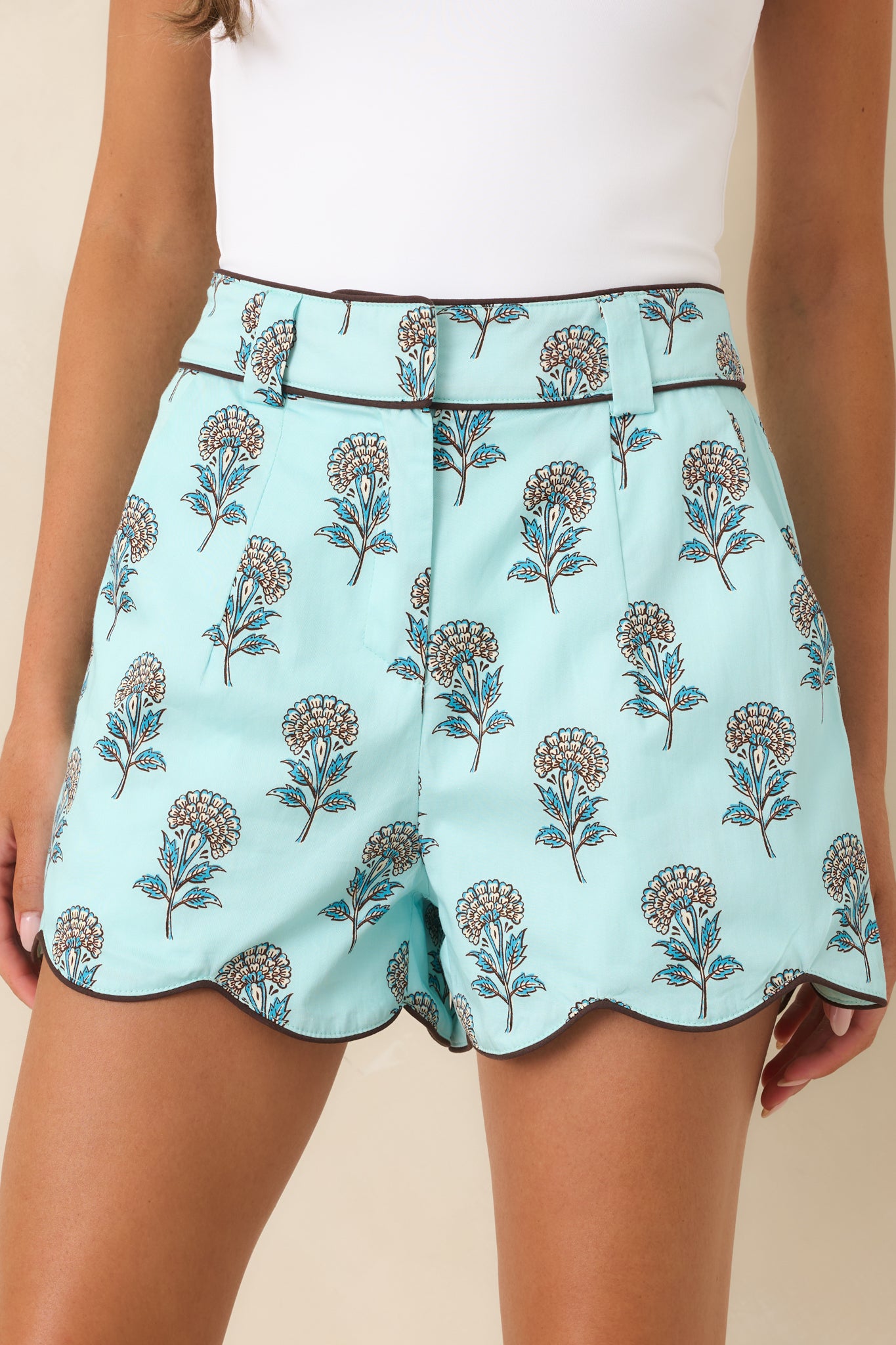 Chocolate brown piping accents the waistband and scalloped hem of these floral cotton shorts.