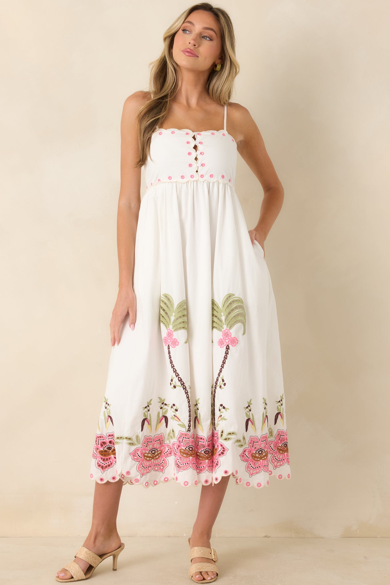 Embroidered midi dress with delicate straps, a structured bodice, flowing A-line skirt, and a decorative floral cutwork border.