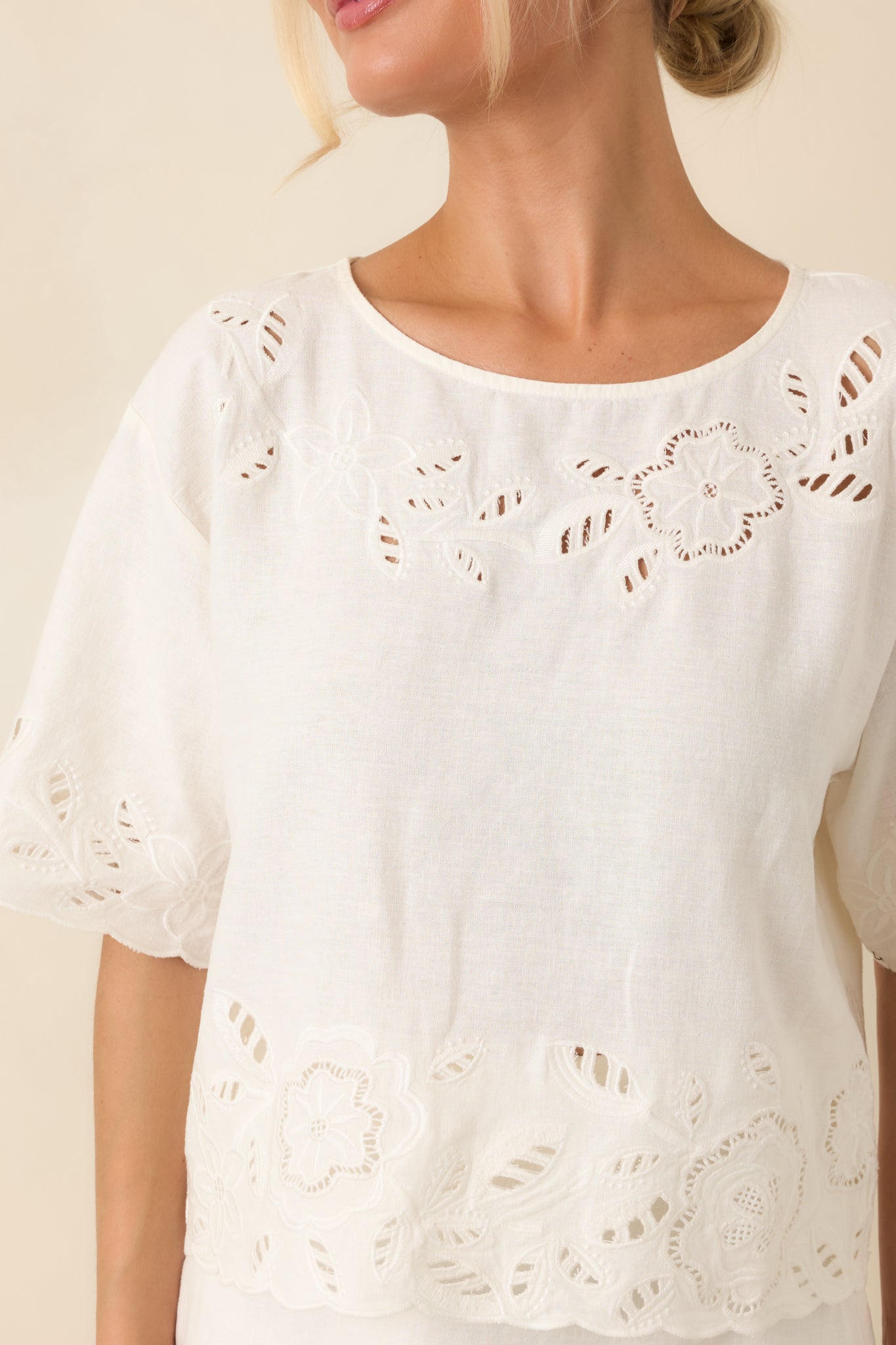 Close-up of the floral cutwork embroidery showcasing the detailed stitching along the neckline and soft linen-blend fabric.