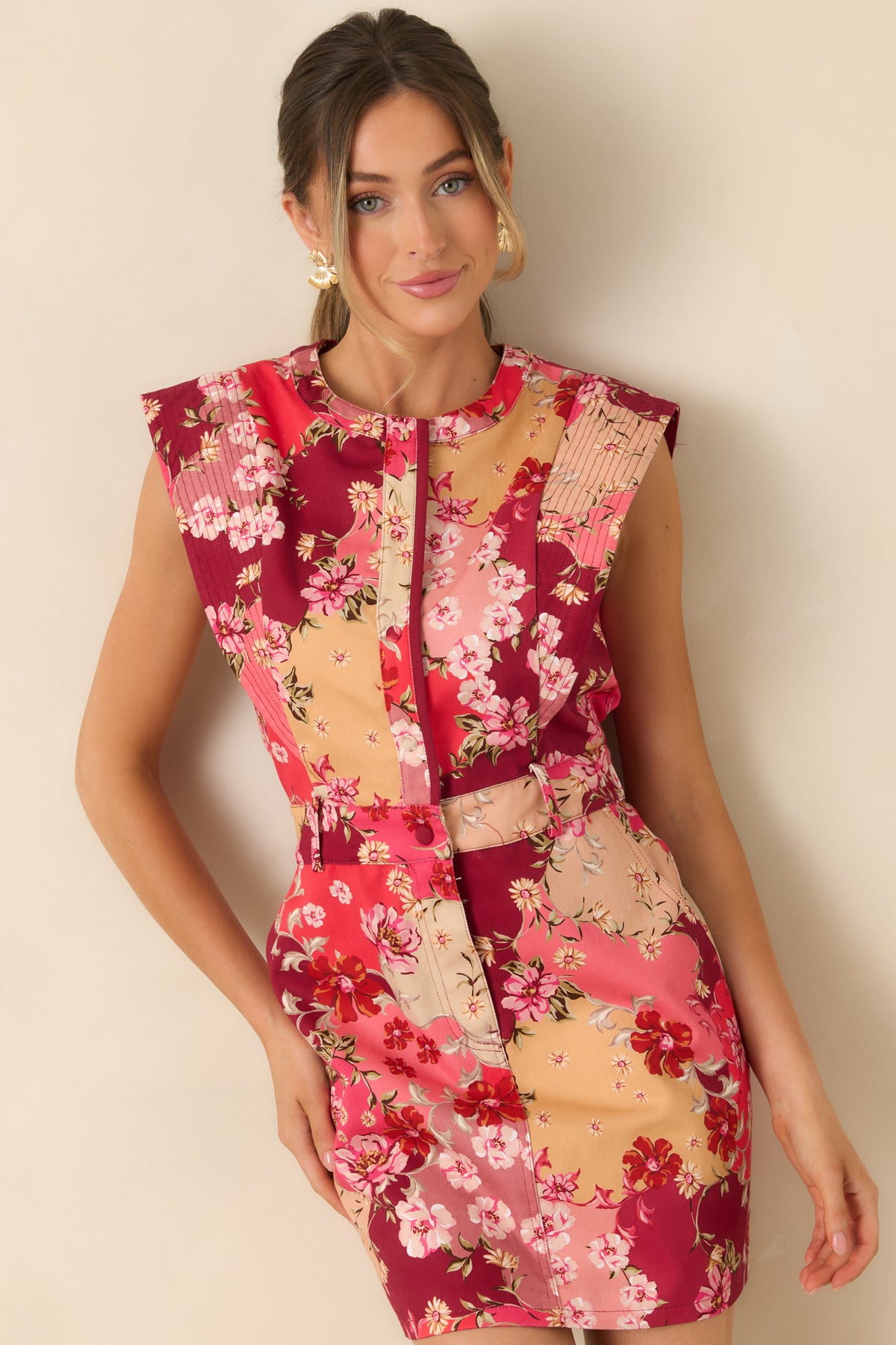 Split neckline and wide shoulder panels frame the floral cotton denim mini dress’s sleeveless bodice.