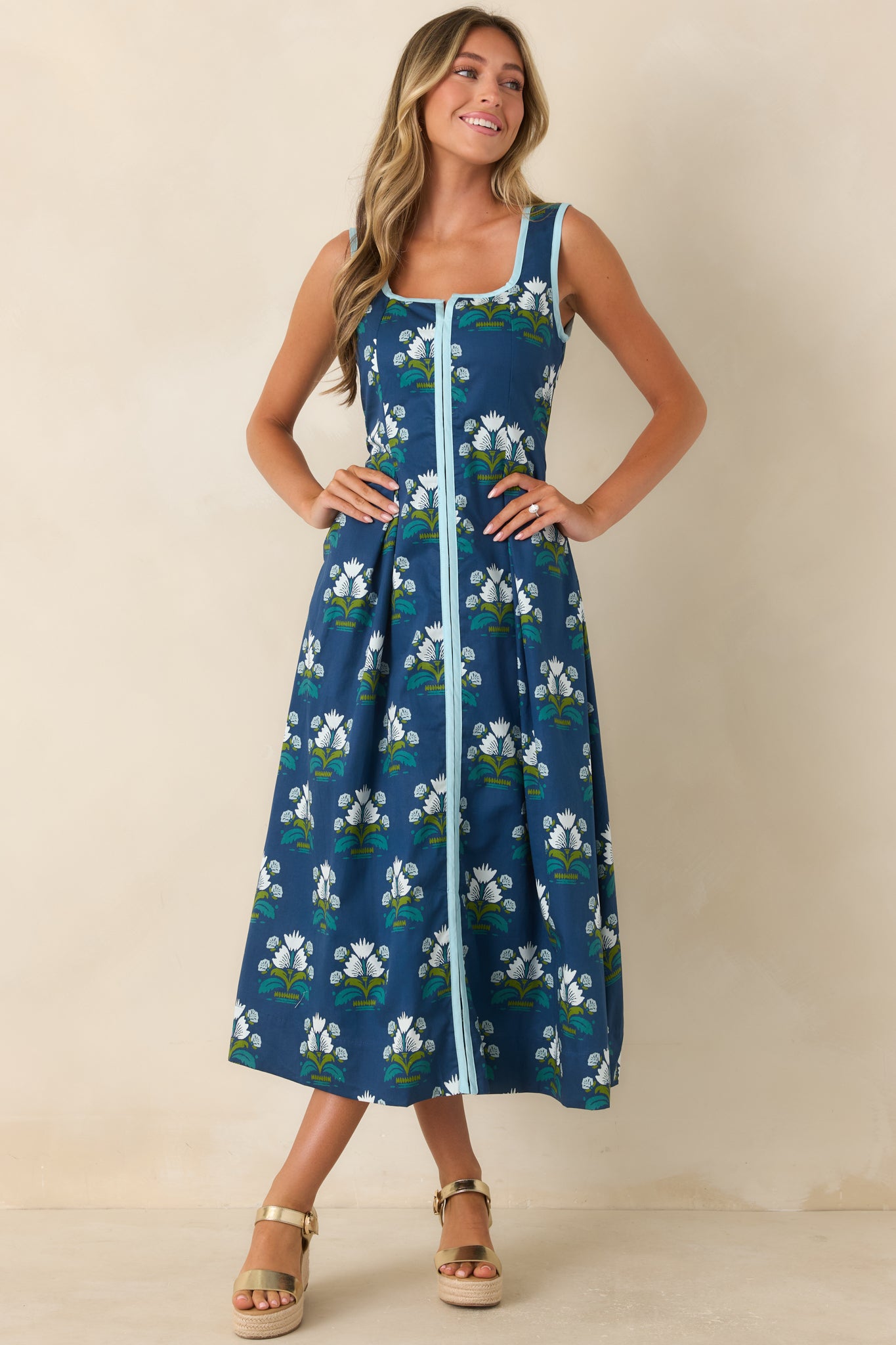 Floral dress with light blue contrast trim, a fitted bodice, and a flowing pleated silhouette.