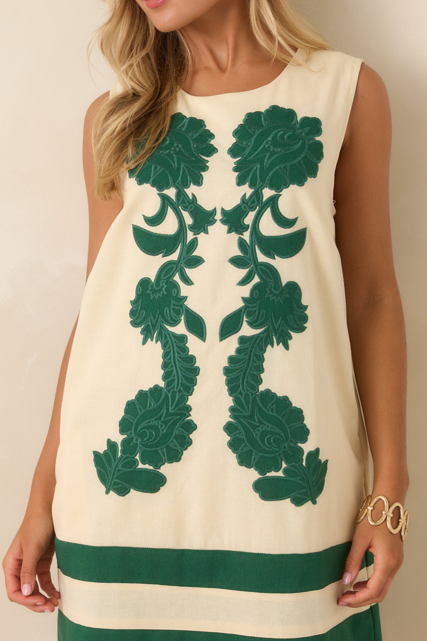 Floral embroidered dress showcasing the round neckline, sleeveless design, and contrasting ivory and green color palette.