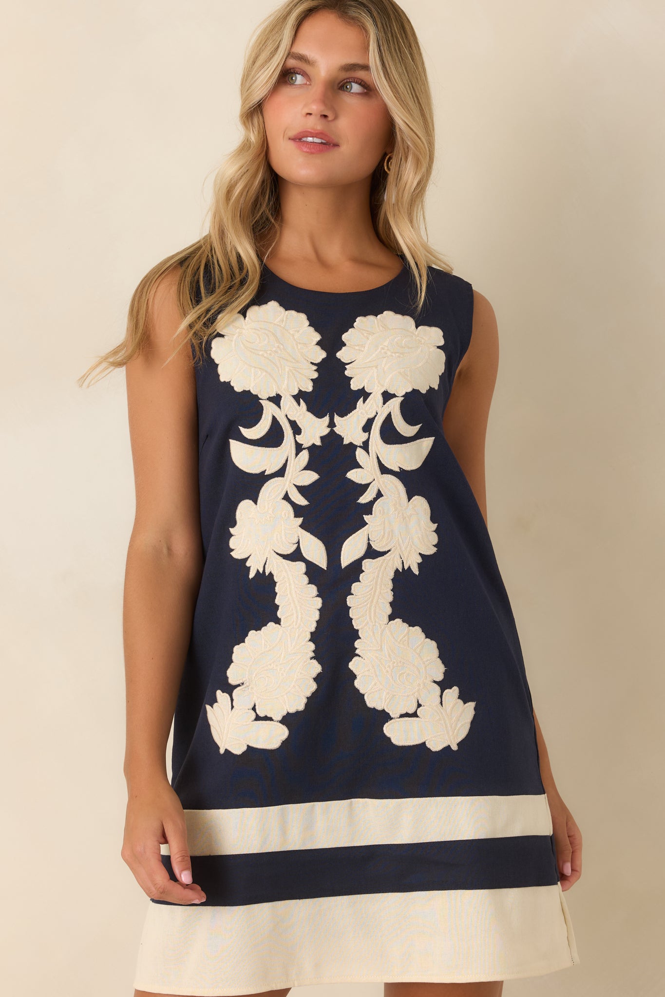 Floral embroidered dress showcasing the round neckline, sleeveless silhouette, and contrasting navy and ivory design.