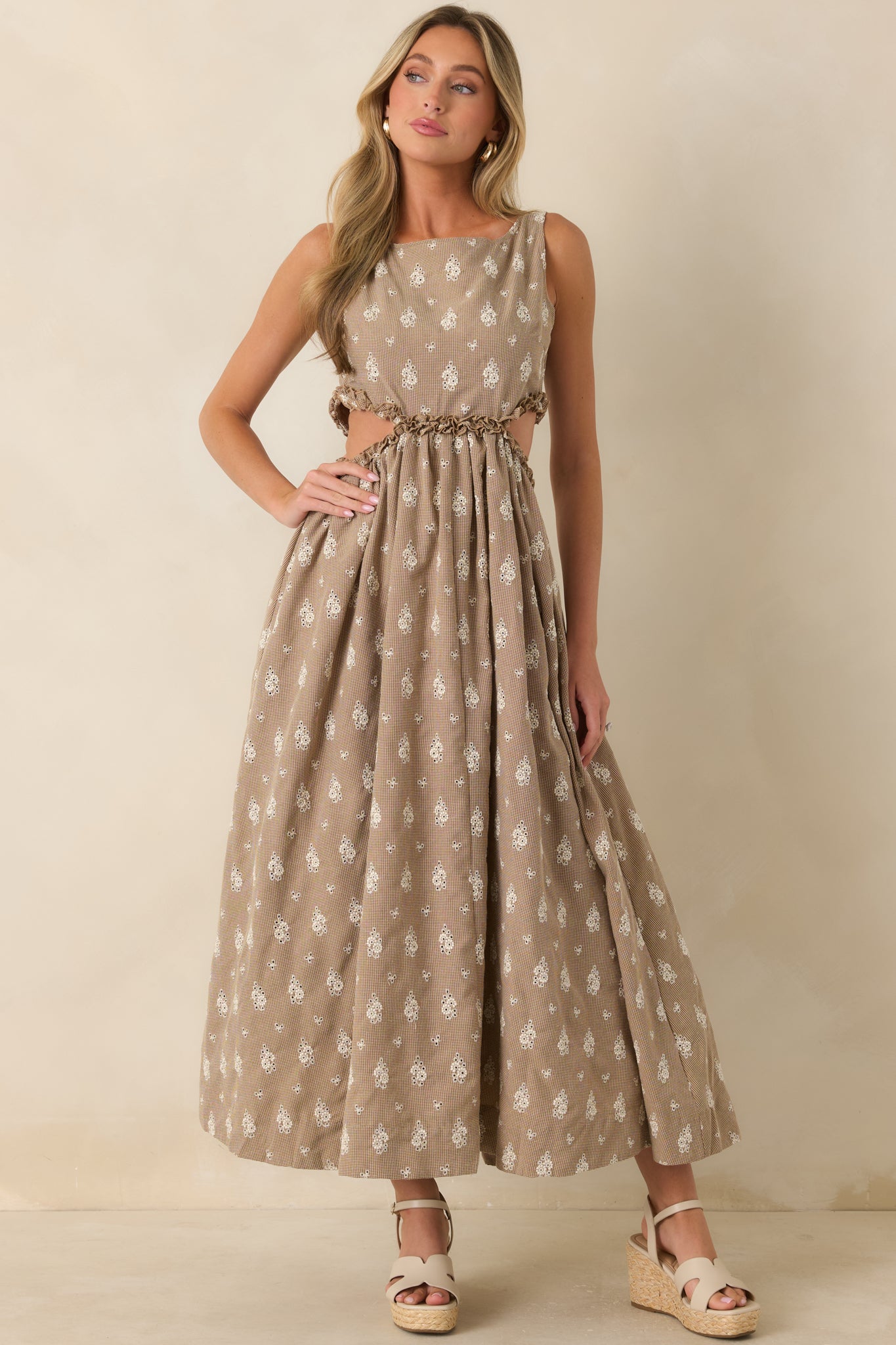 Front view highlighting the boat neckline, gathered waist, and breezy side cut-outs with ruffle detailing on a floral eyelet maxi dress.
