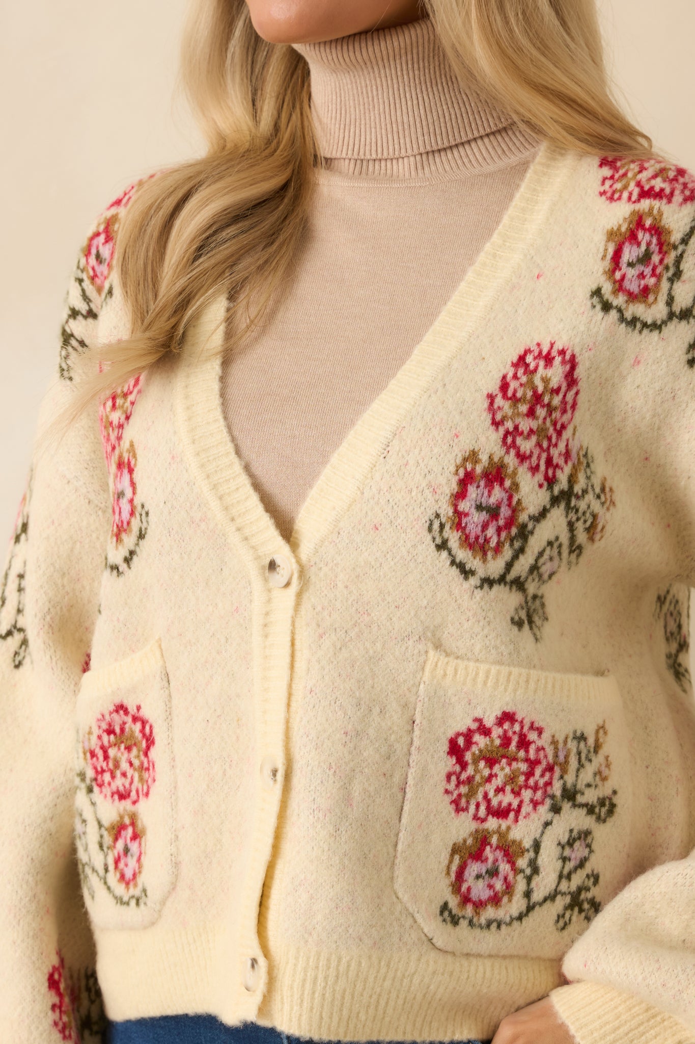 Detailed view of the floral knit design and textured ribbing along the soft ivory yarn